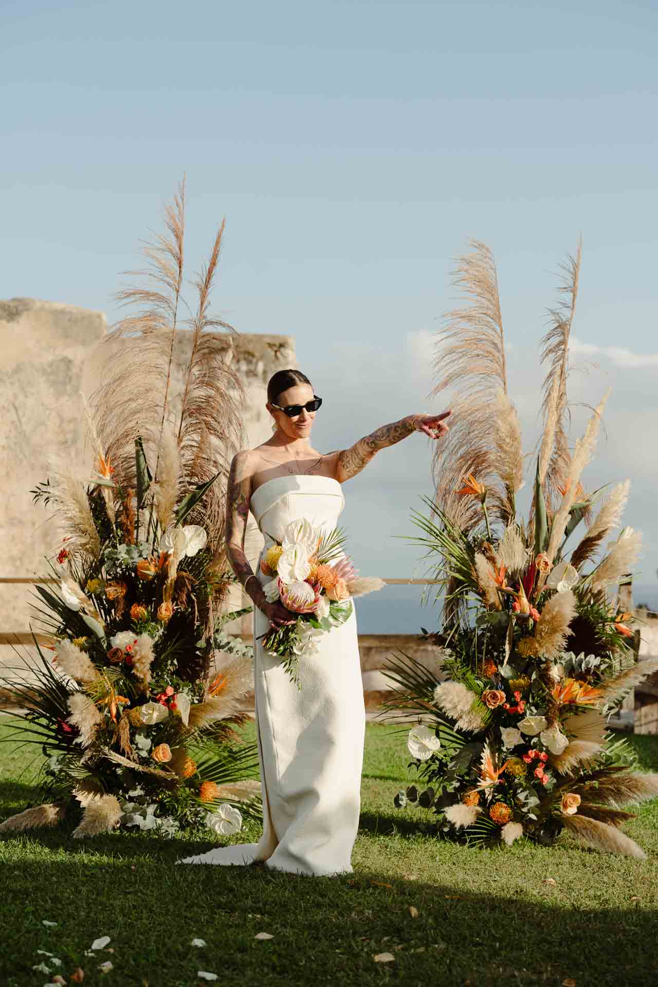 La sposa con gli occhiali da sole indica qualcosa tra le composizioni di pampas