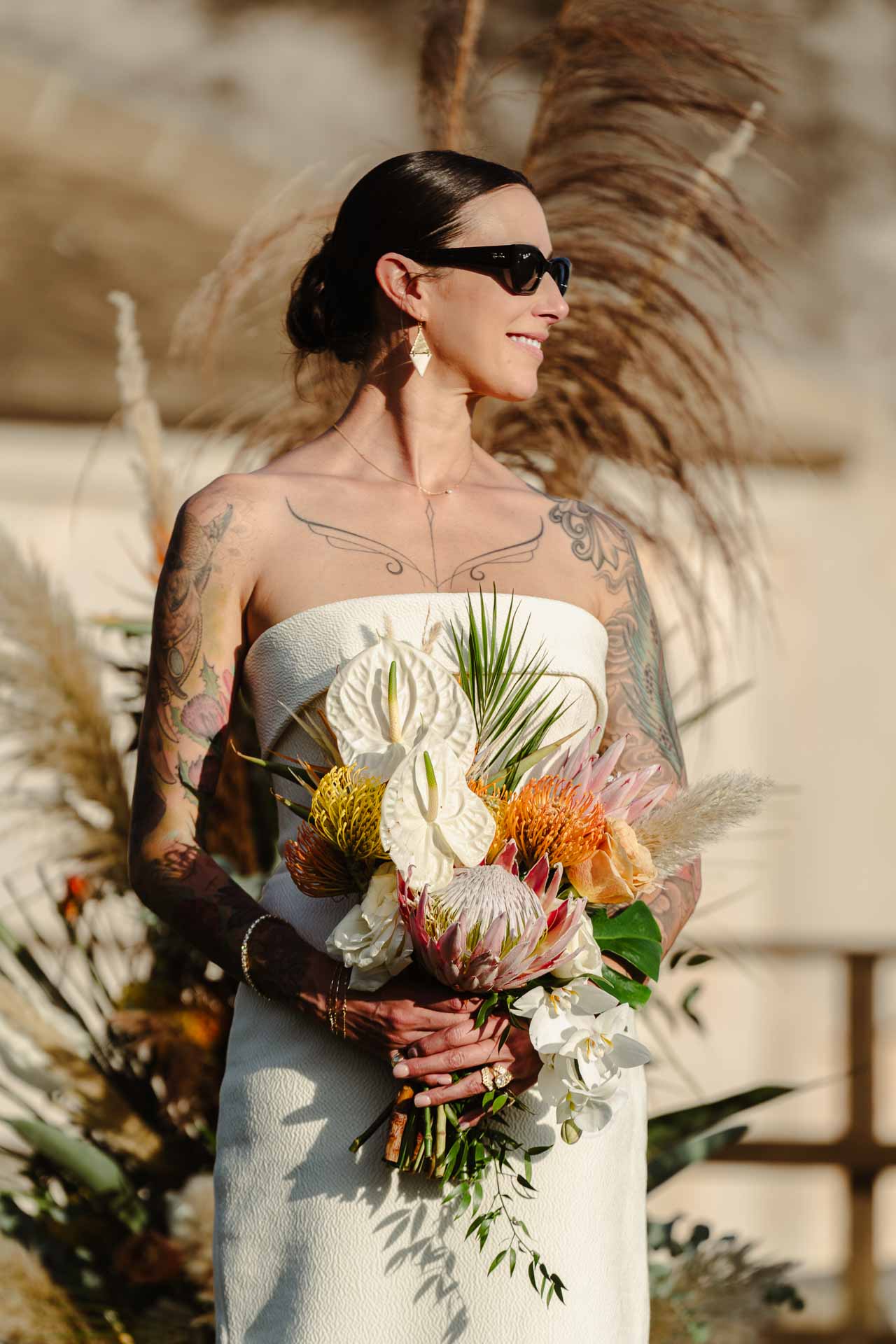 La sposa sorride con il bouquet di protee, davanti ai pampas