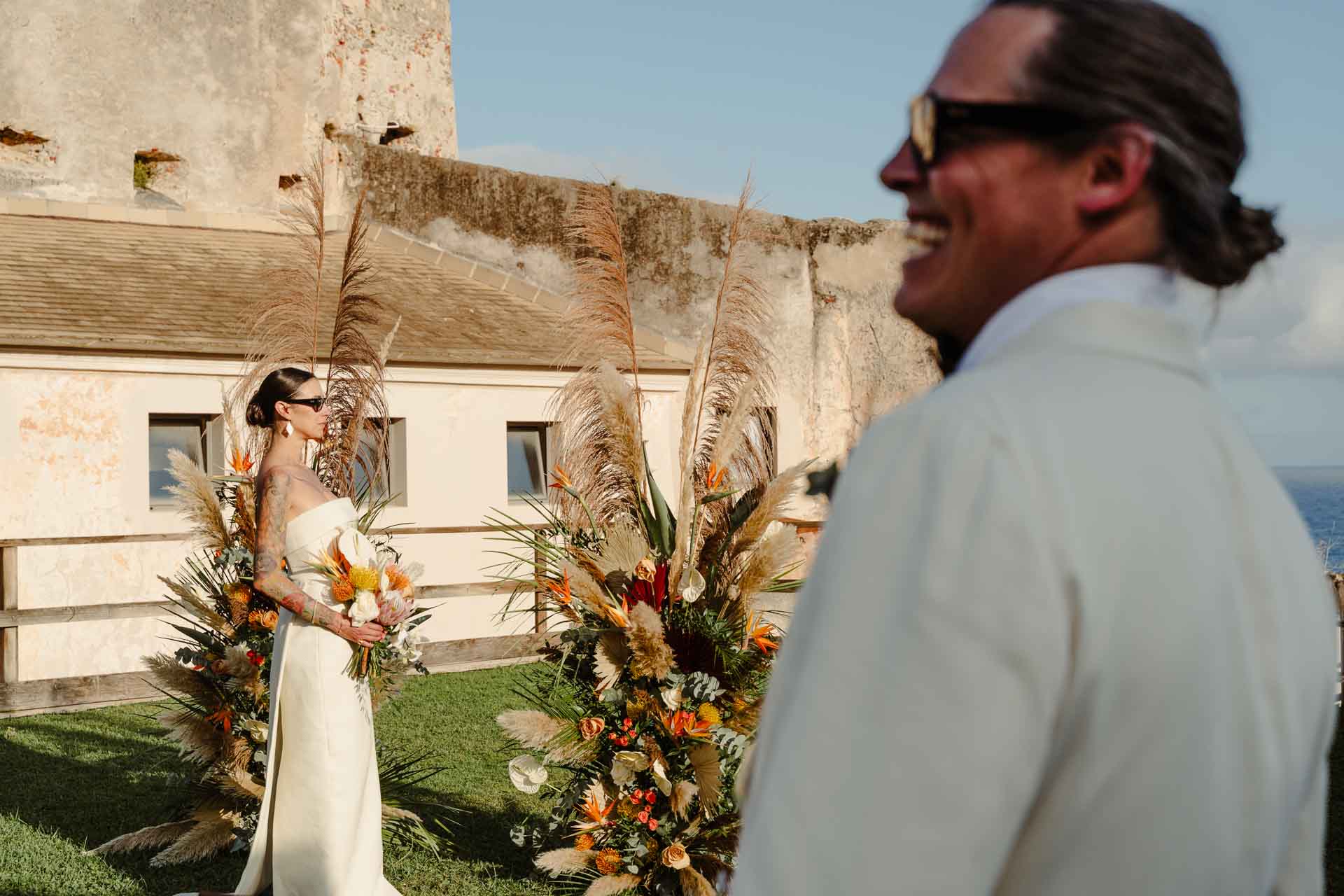 Lo sposo ride guardando la sposa tra i fiori dell'altare