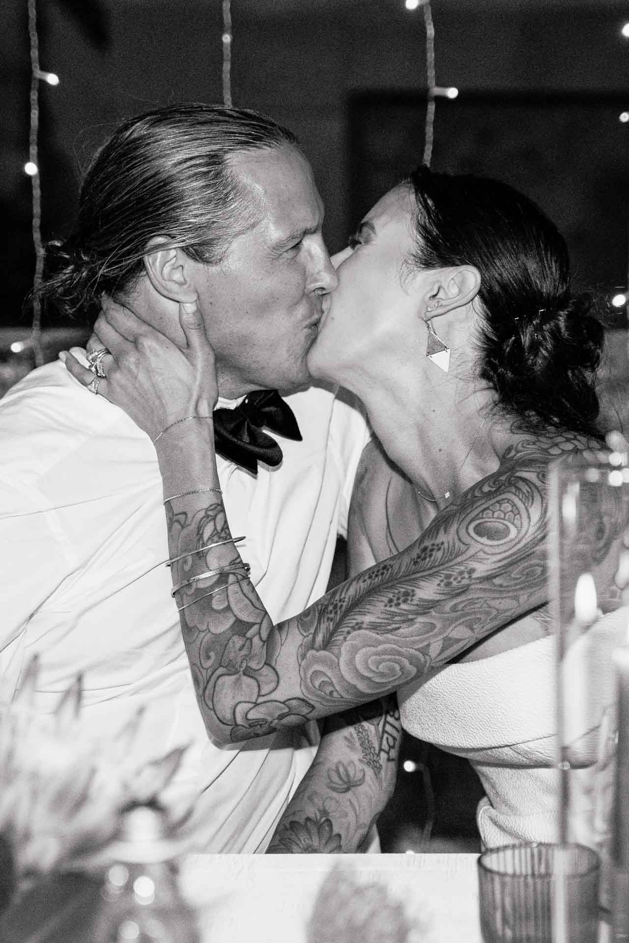 In bianco e nero, il bacio degli sposi, lui le tiene il viso