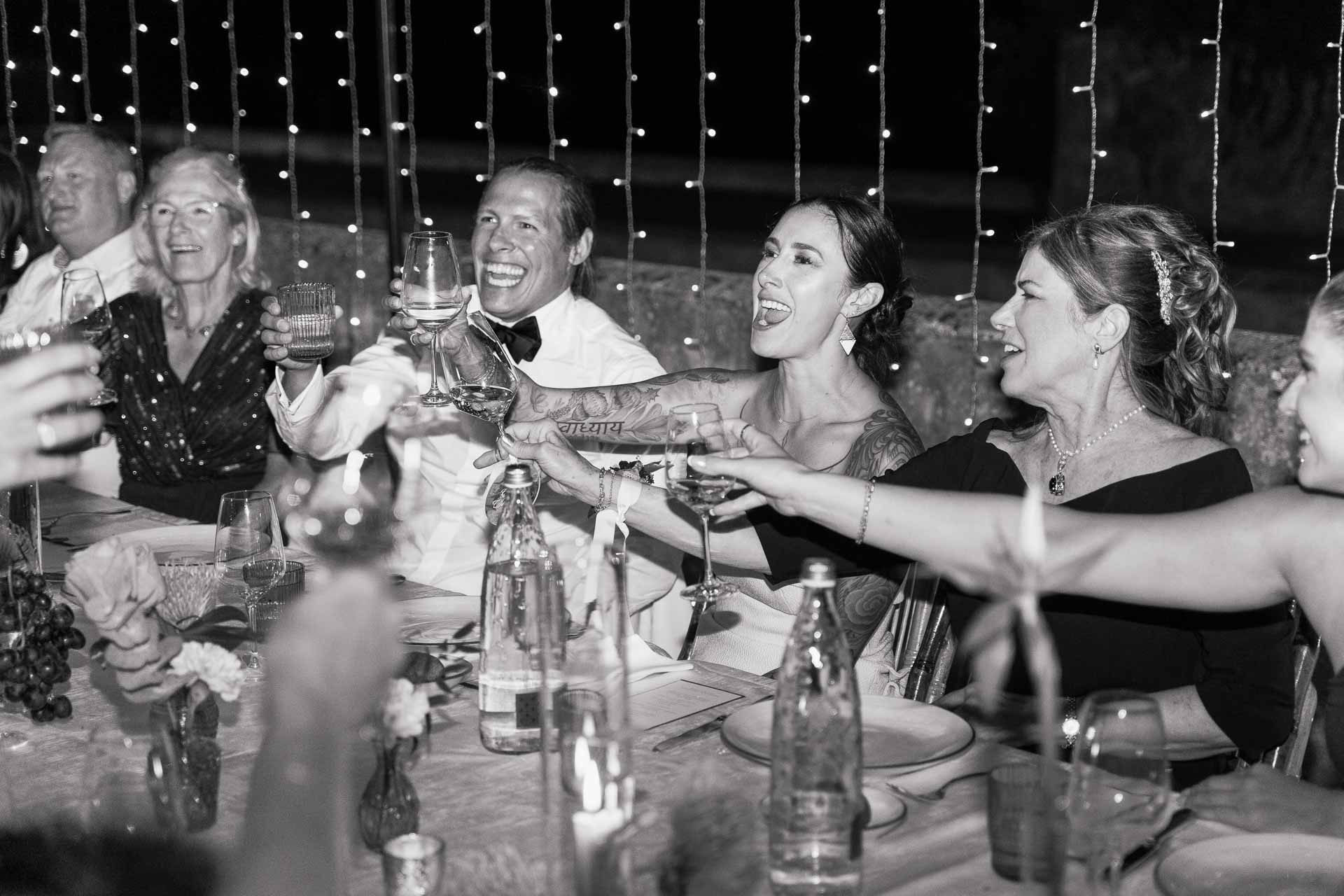In bianco e nero, il brindisi degli sposi con gli invitati a tavola