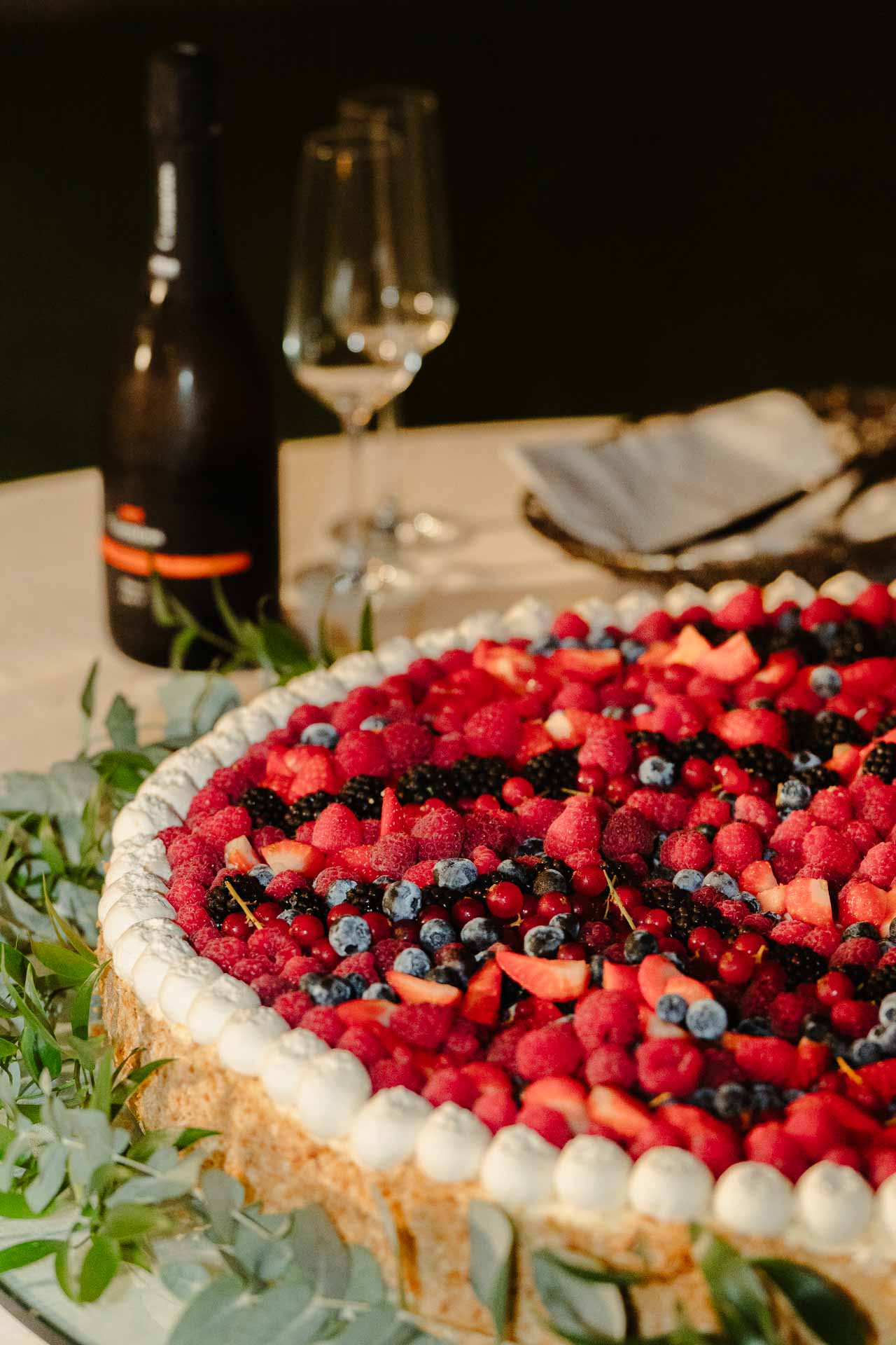 La torta alla frutta con lamponi e mirtilli, accanto allo spumante