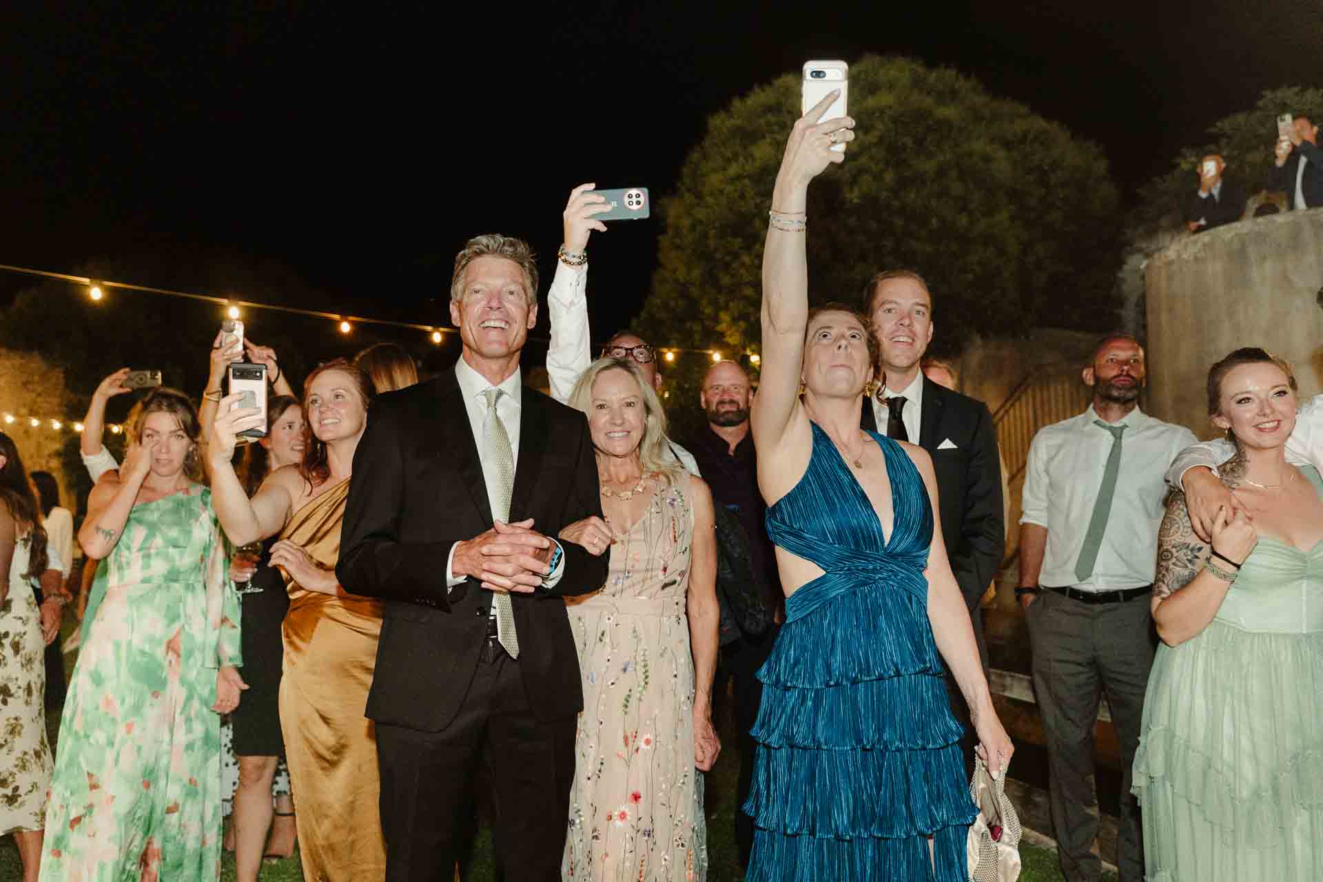 Di sera, gli invitati alzano i telefoni per filmare gli sposi