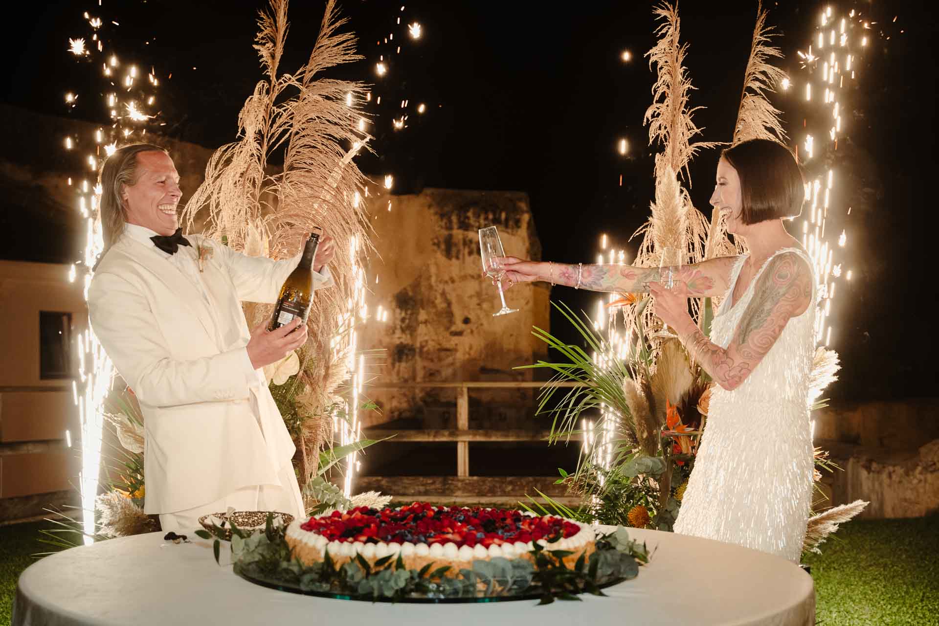 Lo sposo stappa lo spumante e la sposa allunga il calice, tra le scintille
