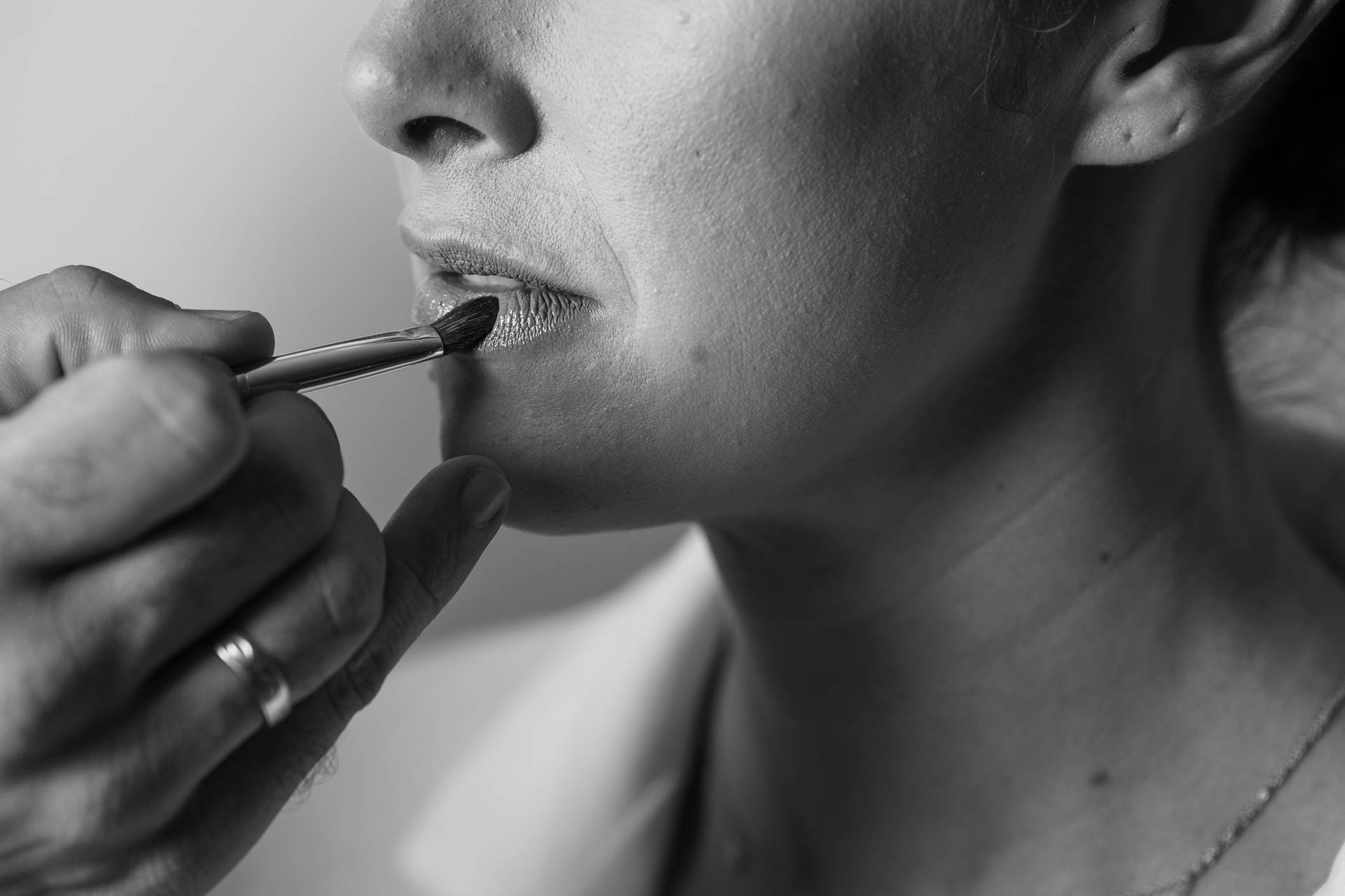 In bianco e nero, il pennello del rossetto sulle labbra della sposa