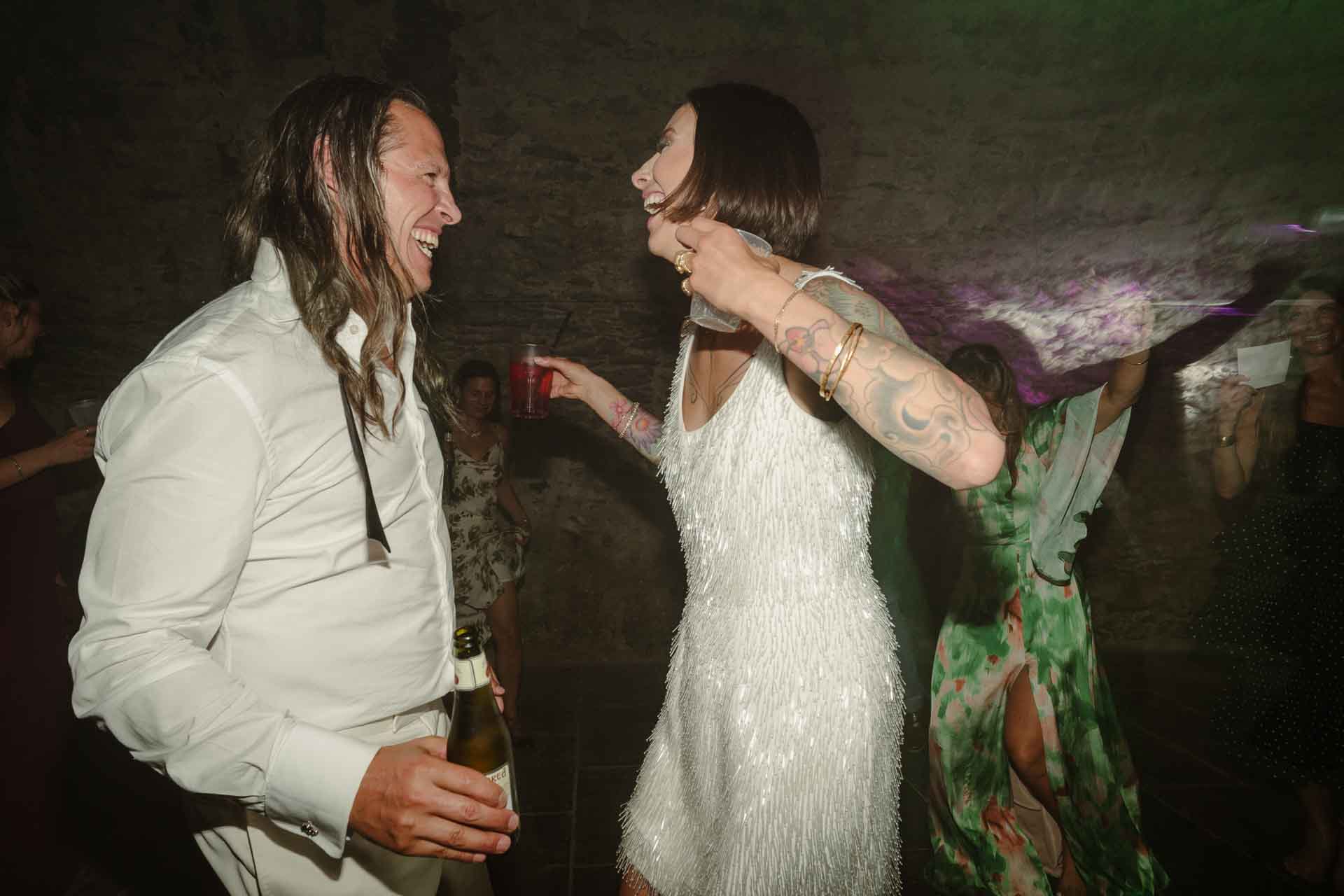 Lo sposo con i capelli sciolti e la sposa ridono ballando