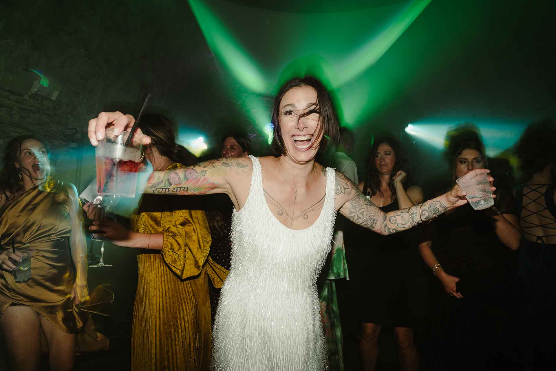 La sposa balla con le braccia aperte, nella luce verde