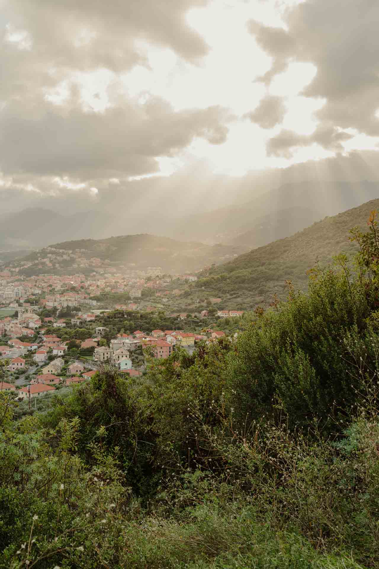 I raggi del sole tra le nuvole sopra la valle e le case di Finale