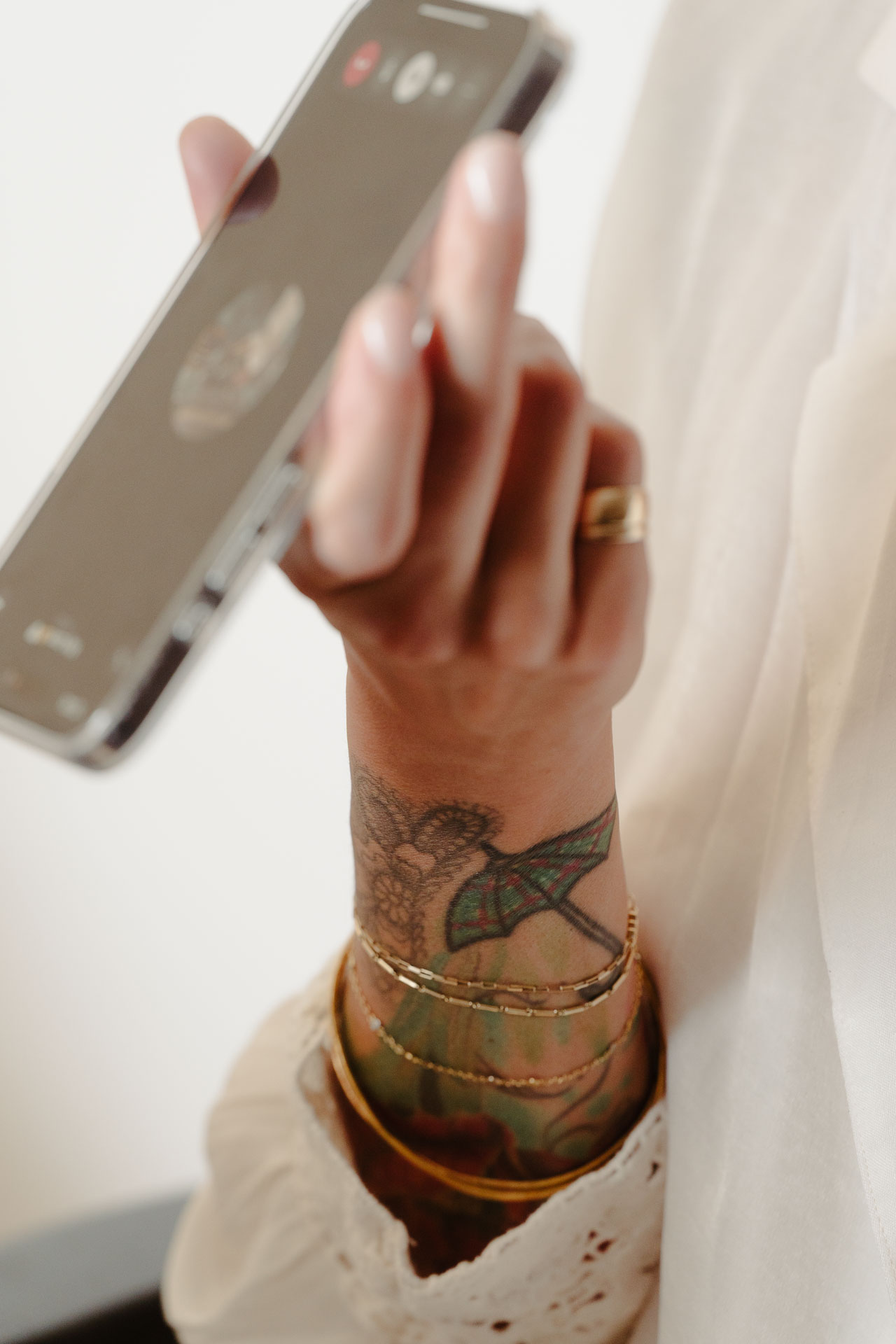 La sposa si guarda nel telefono, con i bracciali e il tatuaggio sul polso
