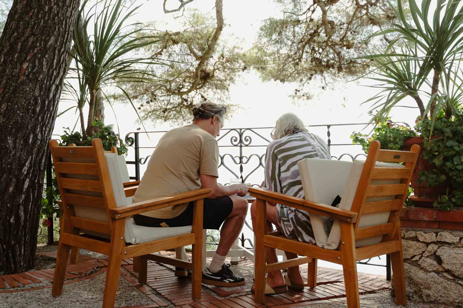 Lo sposo e un amico parlano sulla terrazza, tra i pini e le palme