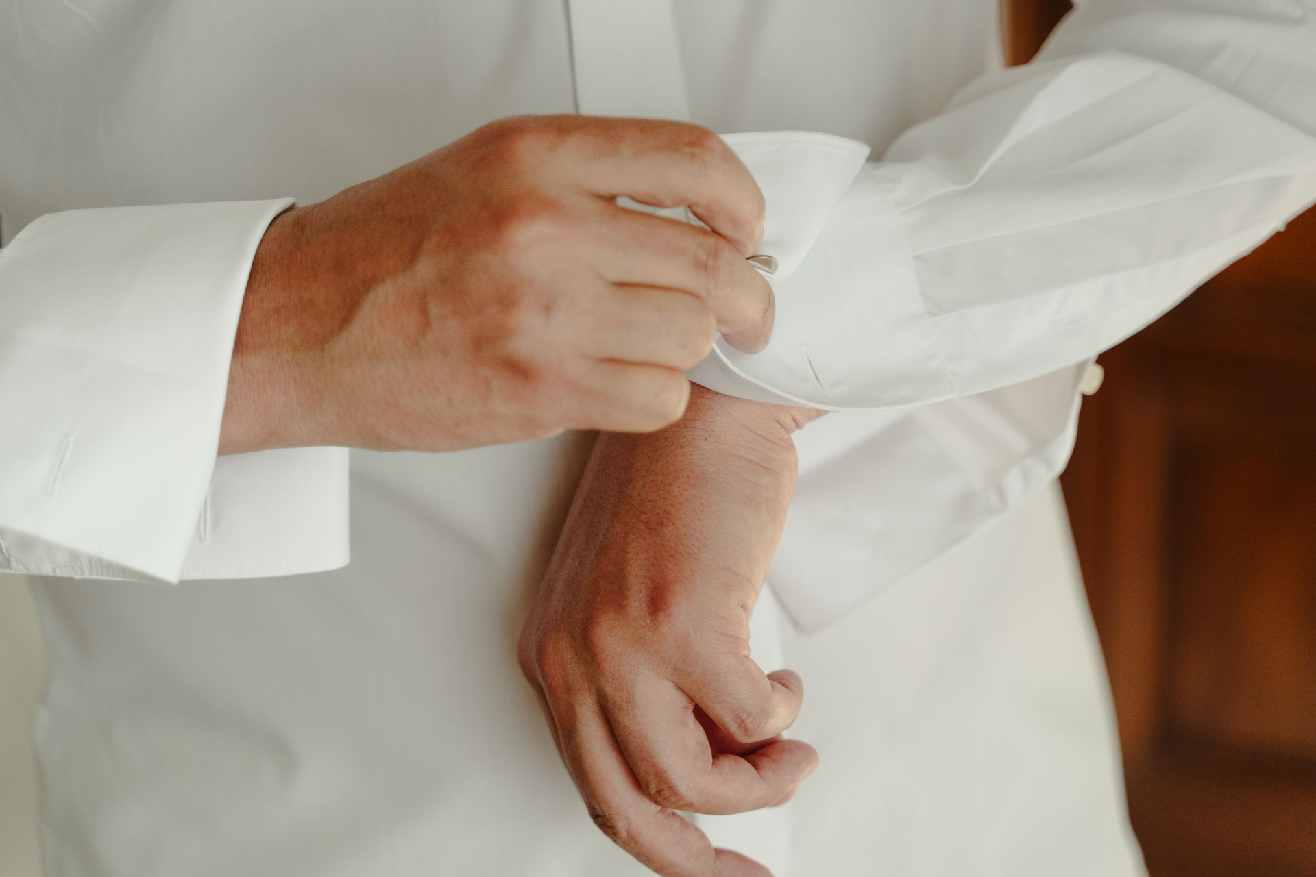 Le mani dello sposo sul polsino della camicia