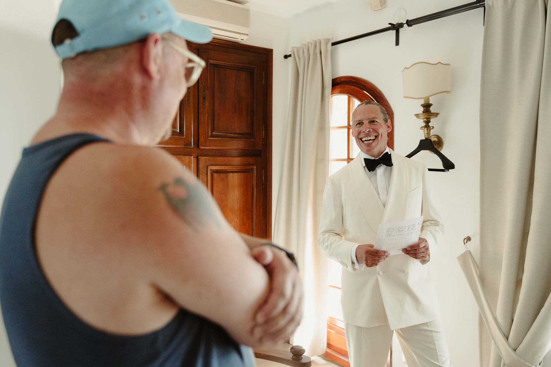 Lo sposo legge un foglio sorridendo, davanti all'amico