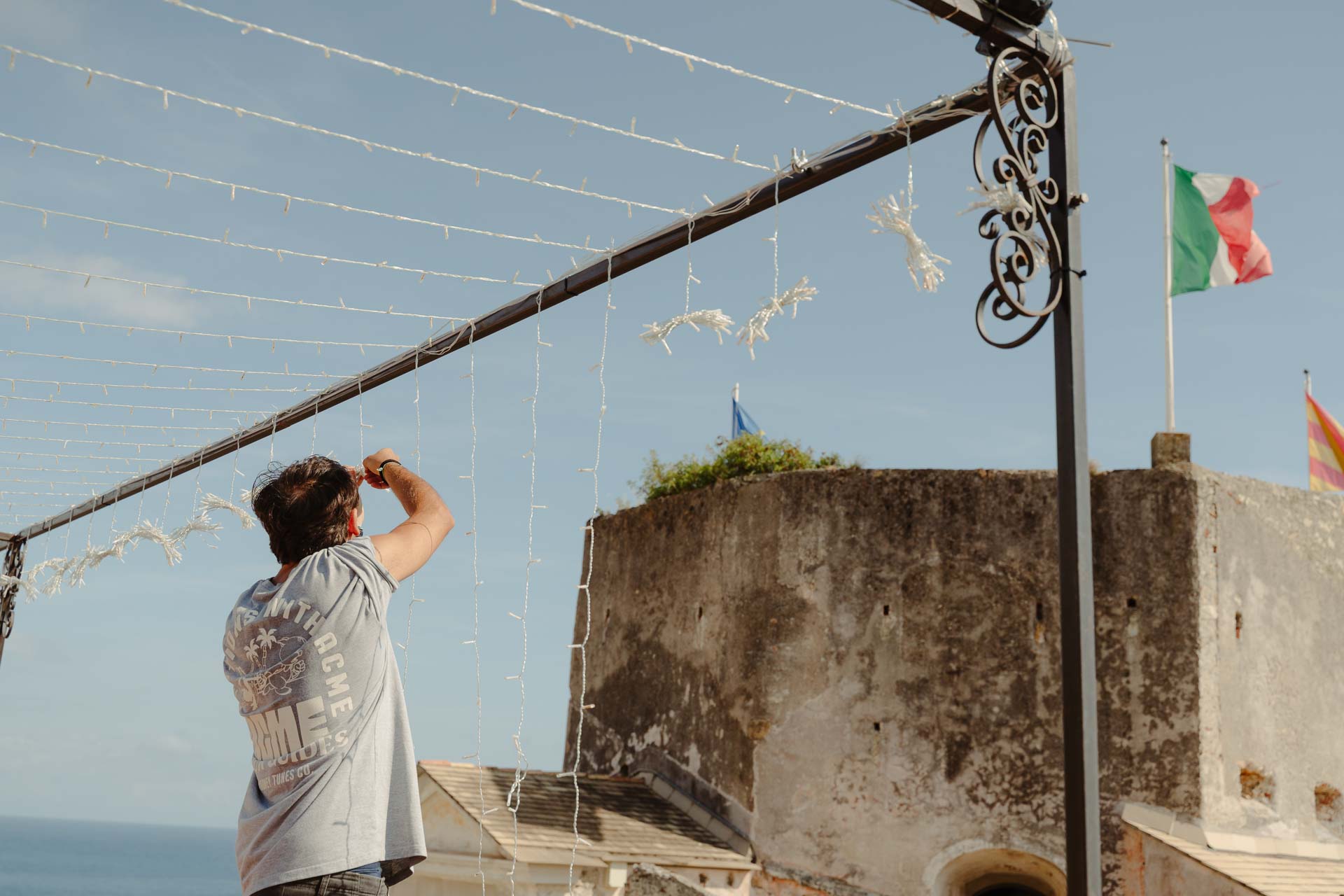 Si appendono le luci sopra la terrazza, accanto alla bandiera italiana