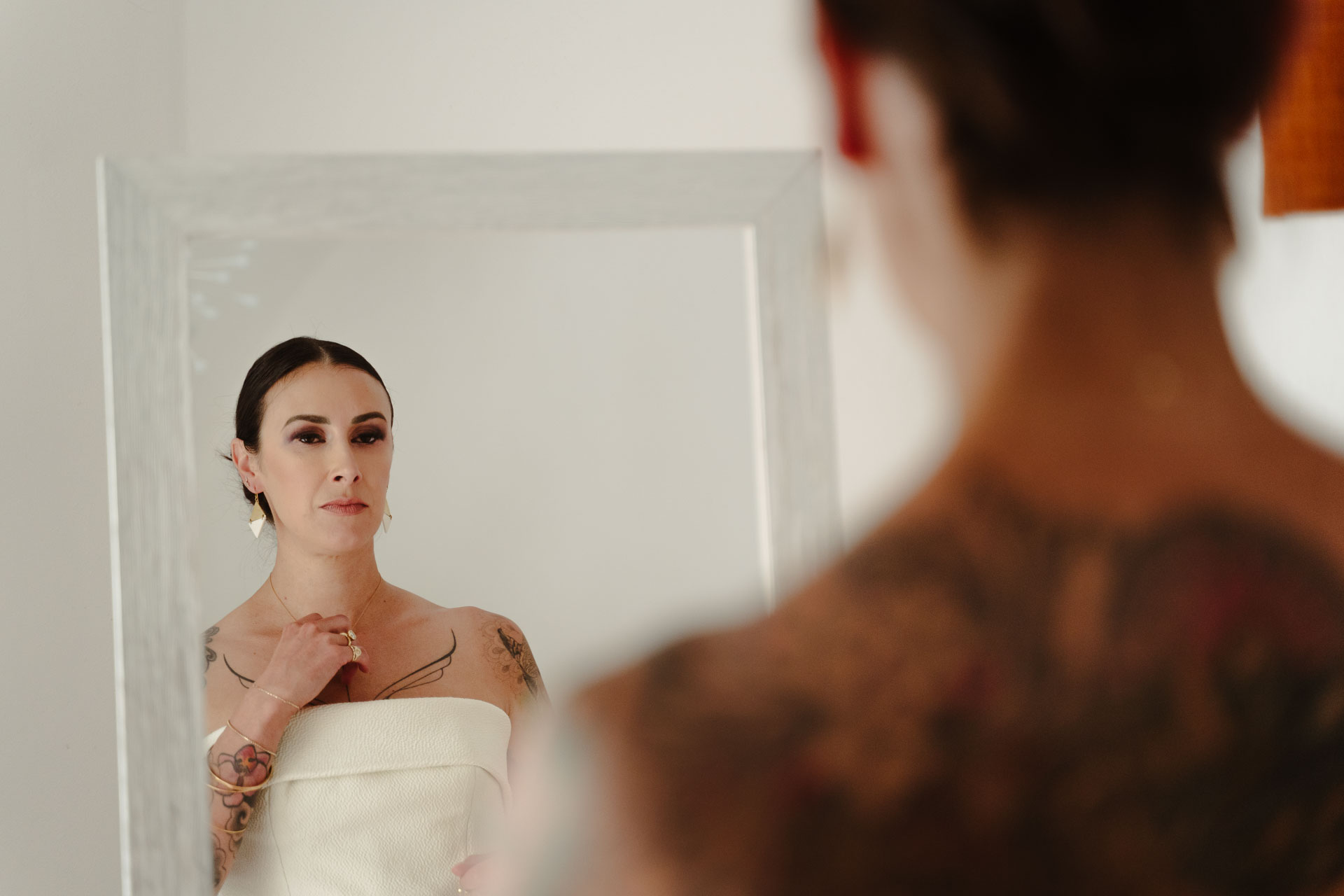 La sposa allo specchio, con la schiena tatuata in primo piano