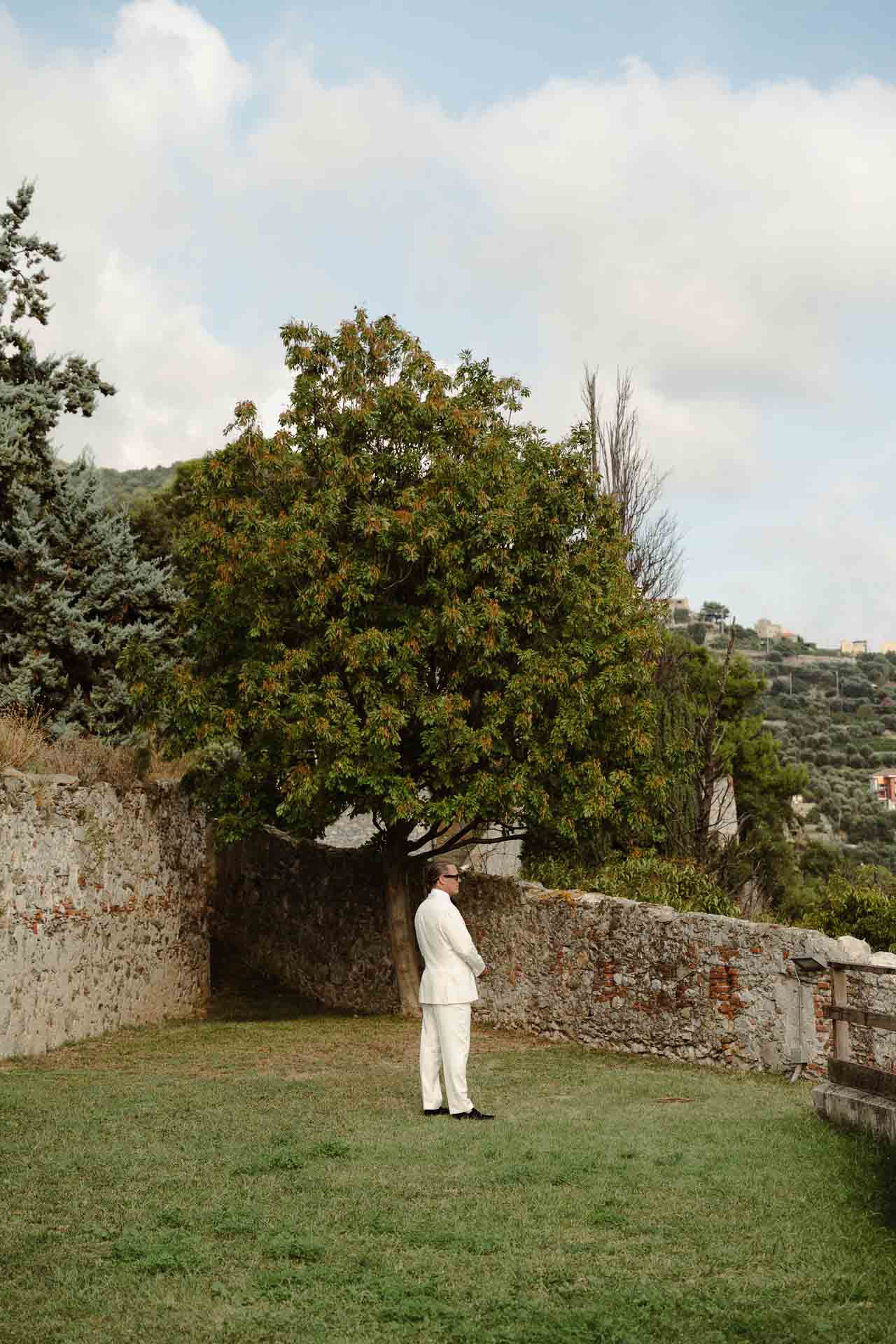 Lo sposo aspetta da solo sul prato tra le mura, prima del primo sguardo