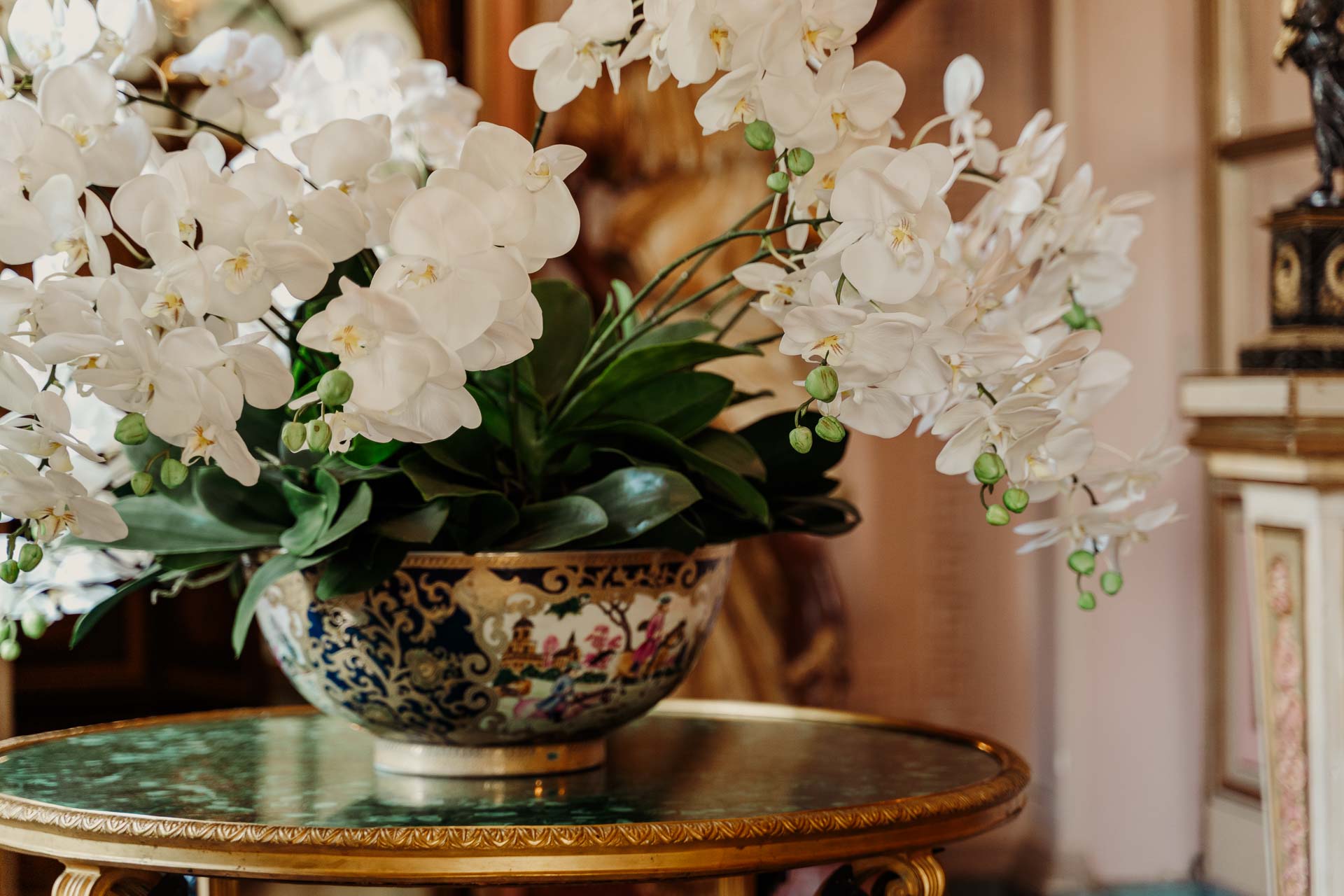 Orchidee bianche in una coppa dipinta, su un tavolino dell'ingresso