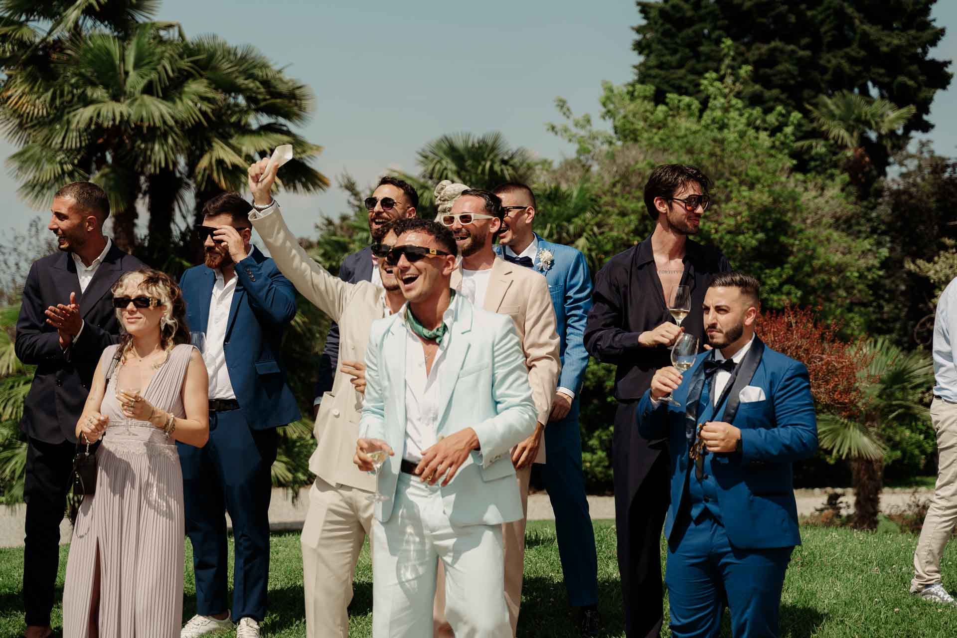 Gli amici dello sposo, con gli occhiali da sole, esultano con i calici in mano
