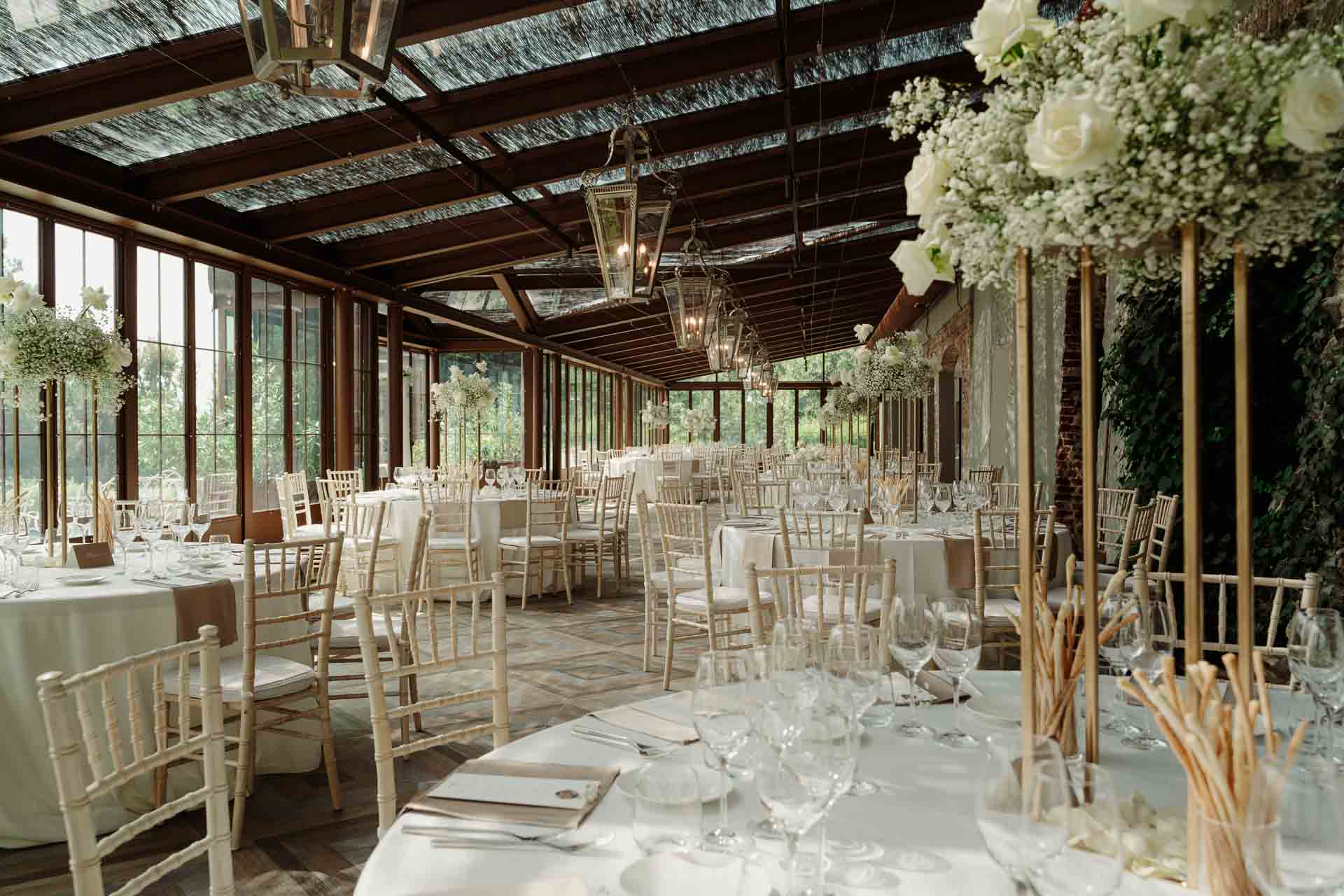 La lunga veranda apparecchiata, con le composizioni di gypsophila alte sui tavoli