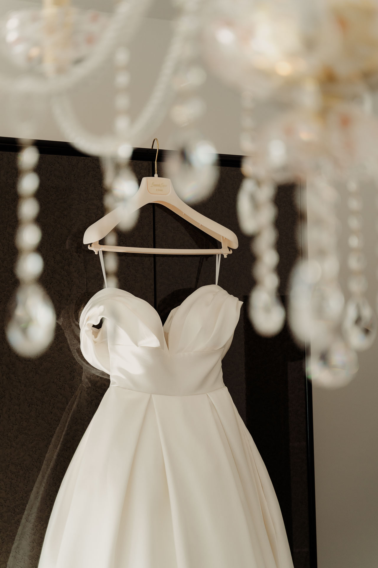 L'abito da sposa appeso sotto un lampadario di cristalli