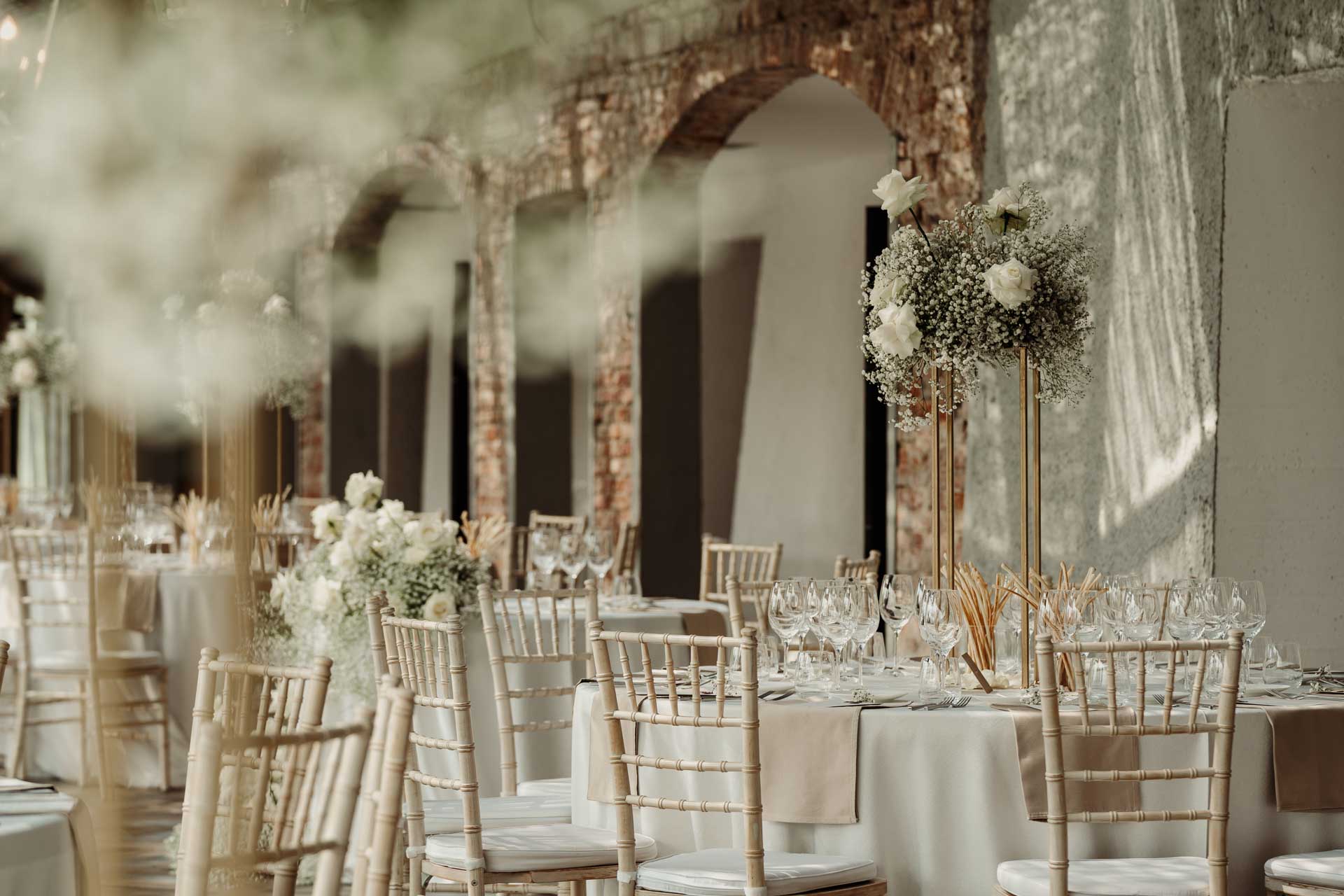 La sala di mattoni e archi apparecchiata, tra i fiori bianchi