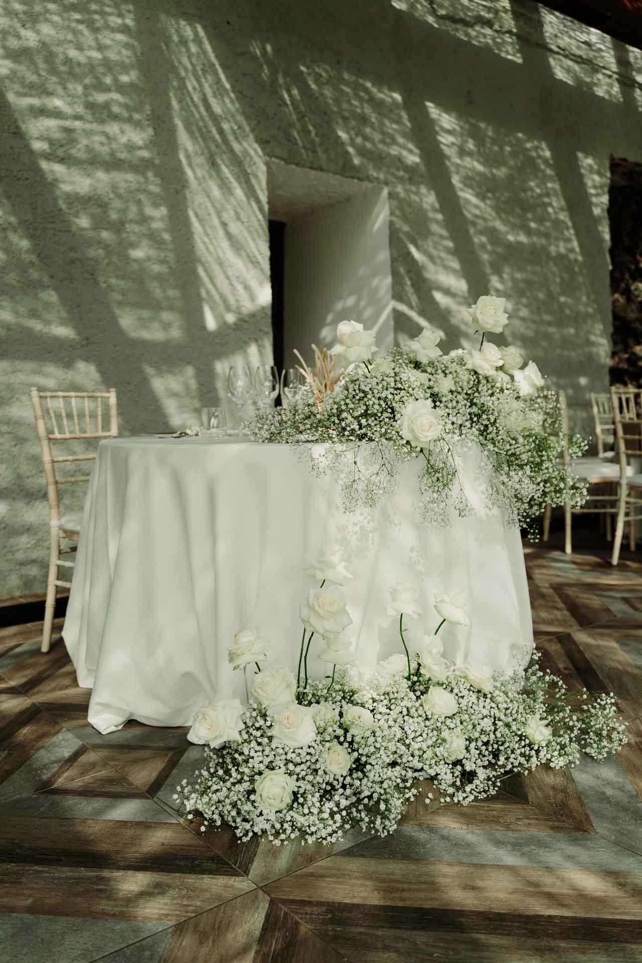 Il tavolo degli sposi con la tovaglia bianca e una cascata di rose e gypsophila, nella veranda