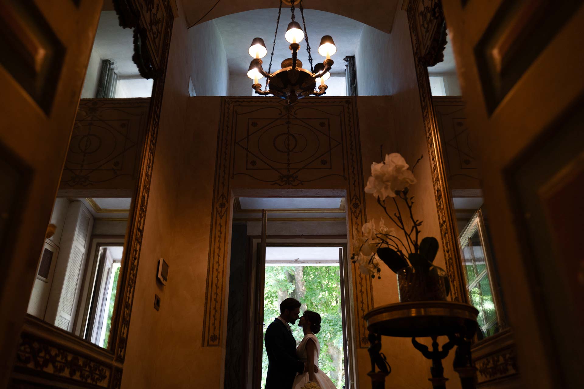 La sala affrescata della villa, con lo sposo e la sposa in controluce sulla porta in fondo
