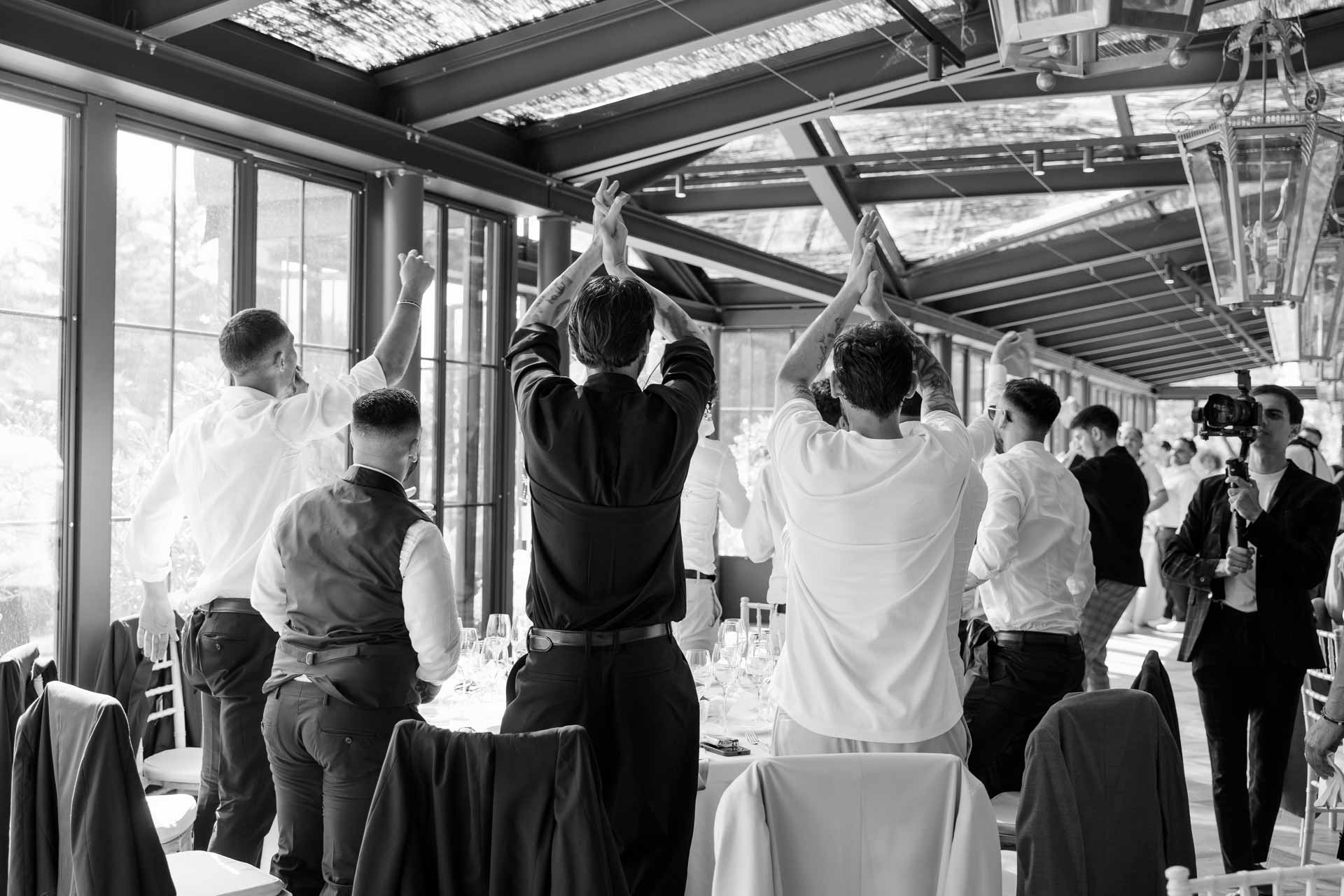 In bianco e nero, gli amici in piedi applaudono con le mani alzate nella veranda
