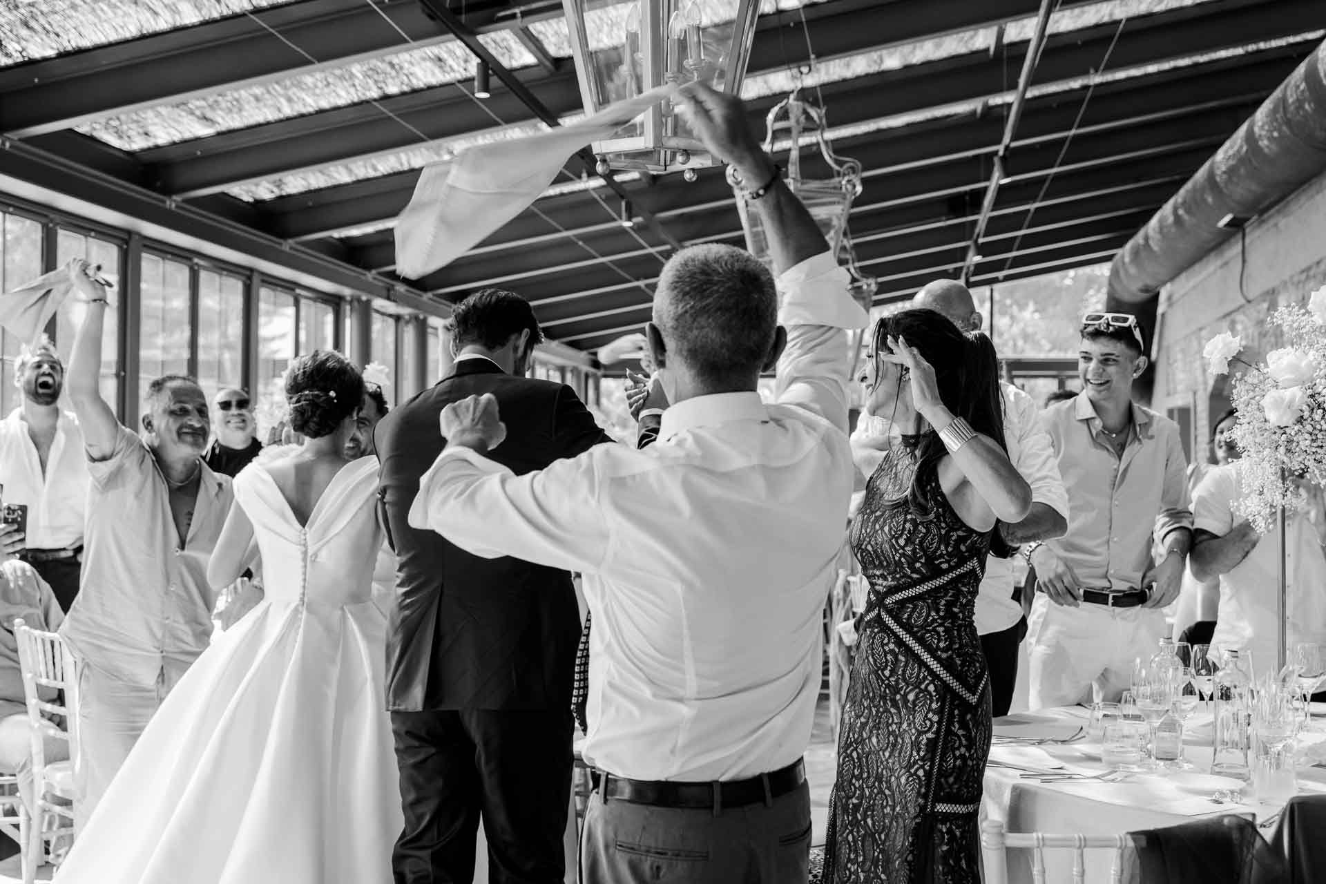 In bianco e nero, gli invitati festeggiano con i tovaglioli al vento all'ingresso degli sposi