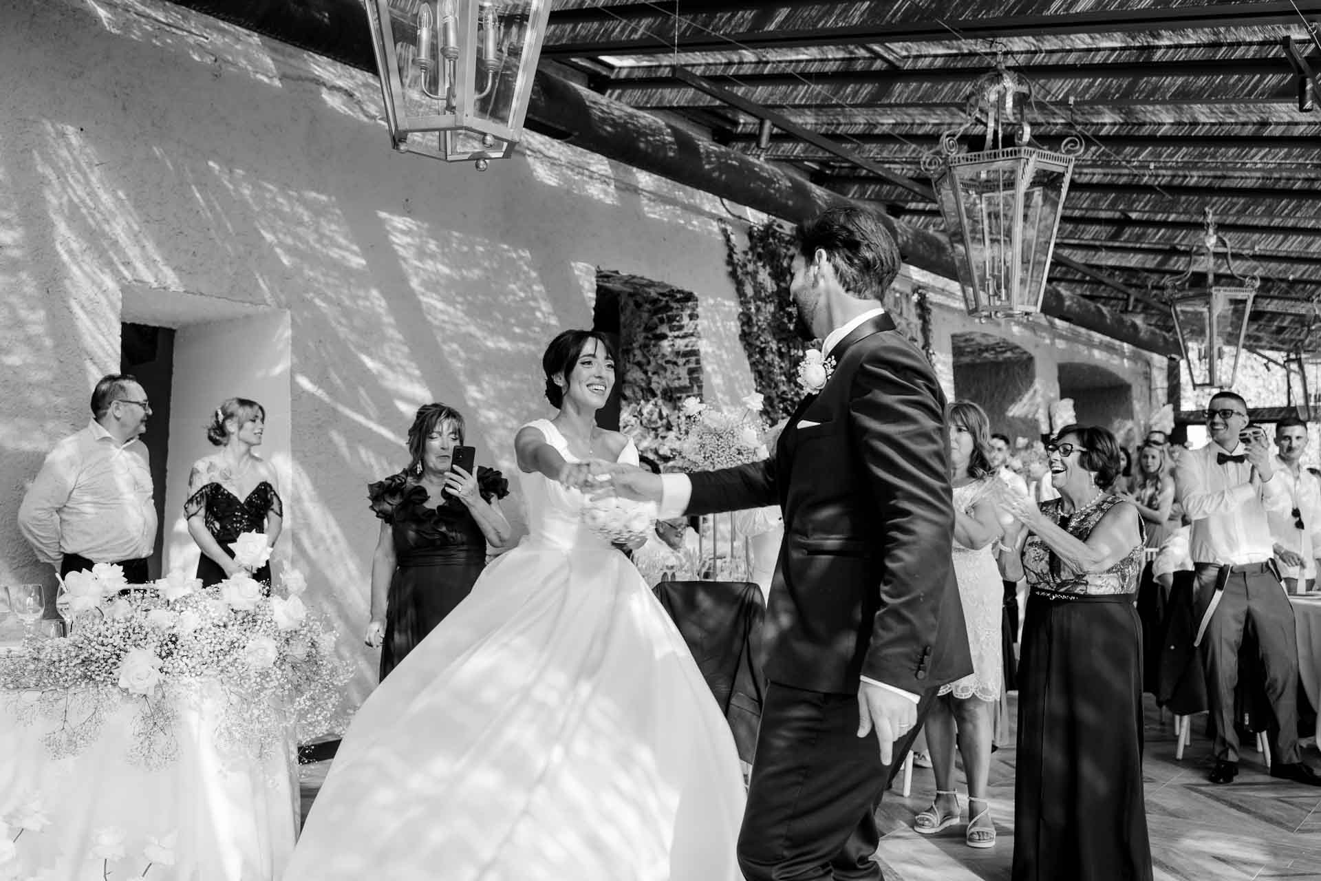 In bianco e nero, gli sposi attraversano la sala tra gli invitati in festa