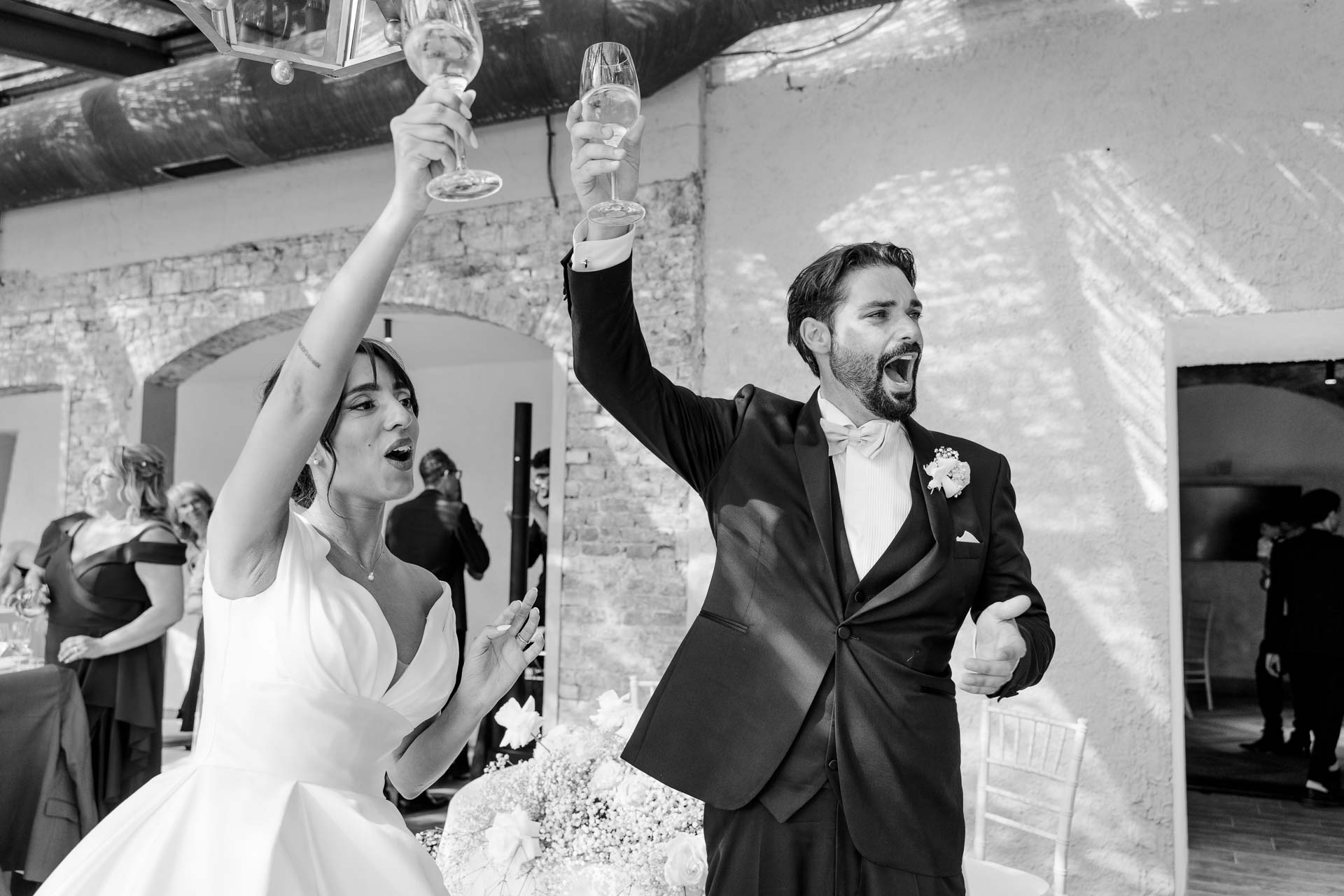 In bianco e nero, gli sposi alzano i calici e urlano di gioia