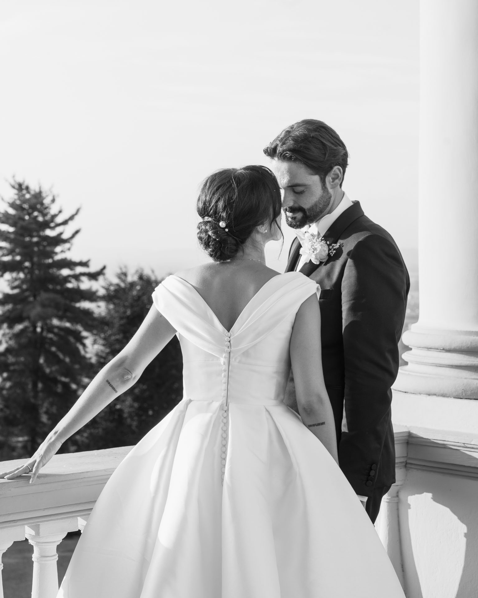 In bianco e nero, gli sposi sulla balconata con la balaustra, lei di schiena con i bottoni dell'abito