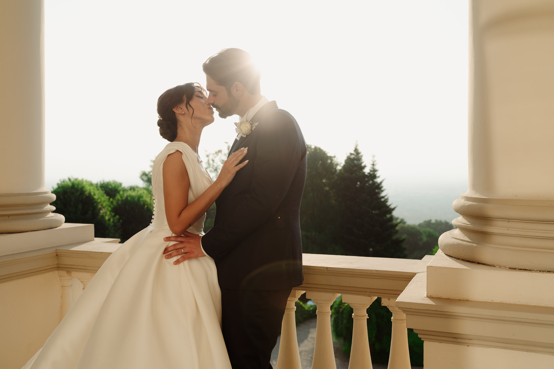 Gli sposi si baciano sulla balconata di Villa Cimena al tramonto, tra le colonne