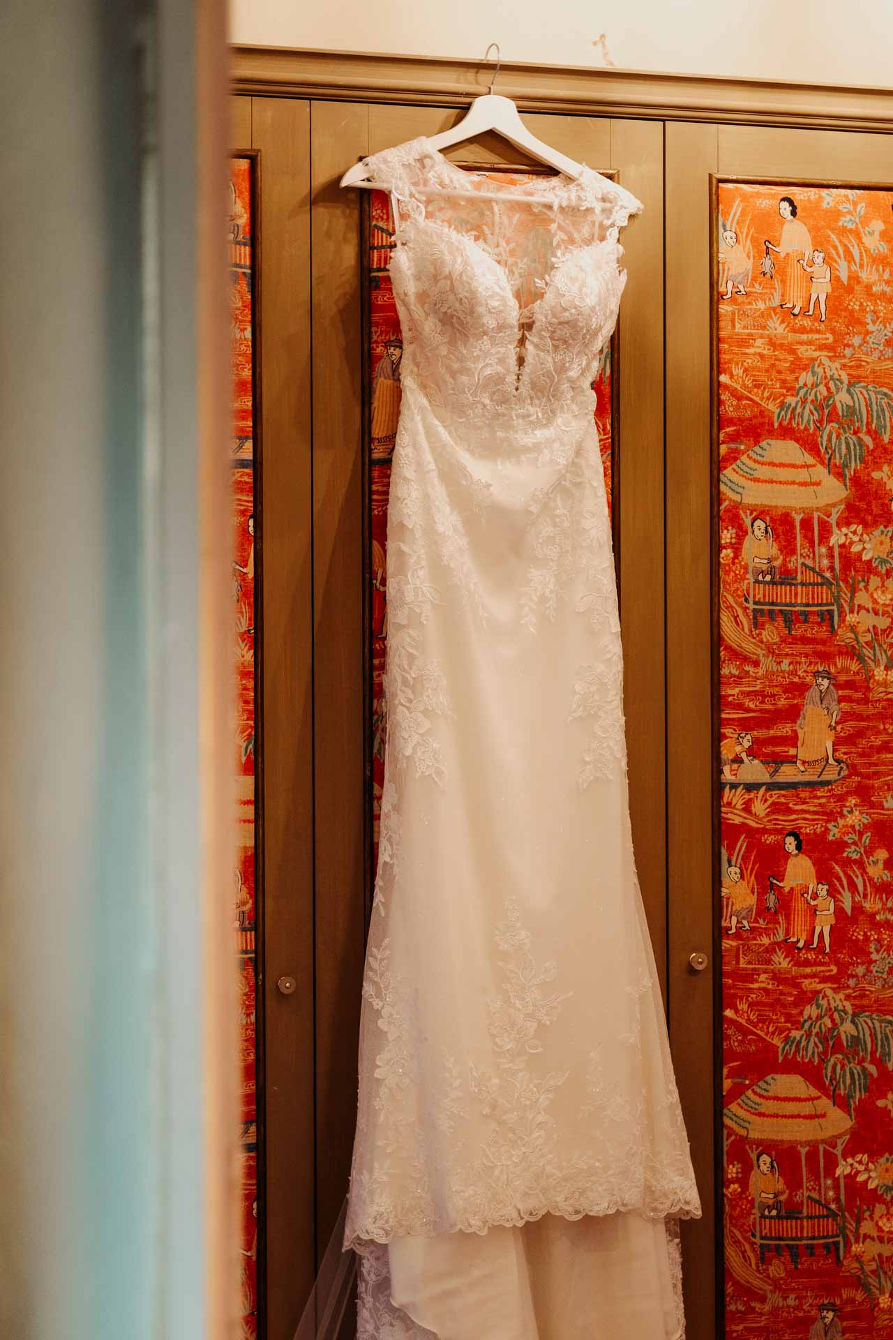 Il secondo abito della sposa, in pizzo, appeso all'armadio con le stampe cinesi rosse