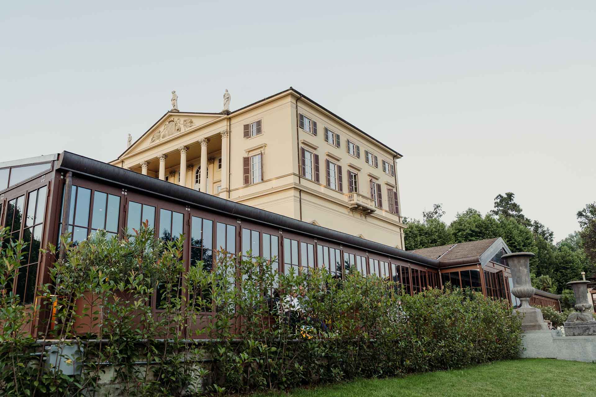 La facciata di Villa Cimena e la veranda viste dal giardino, nella luce della sera