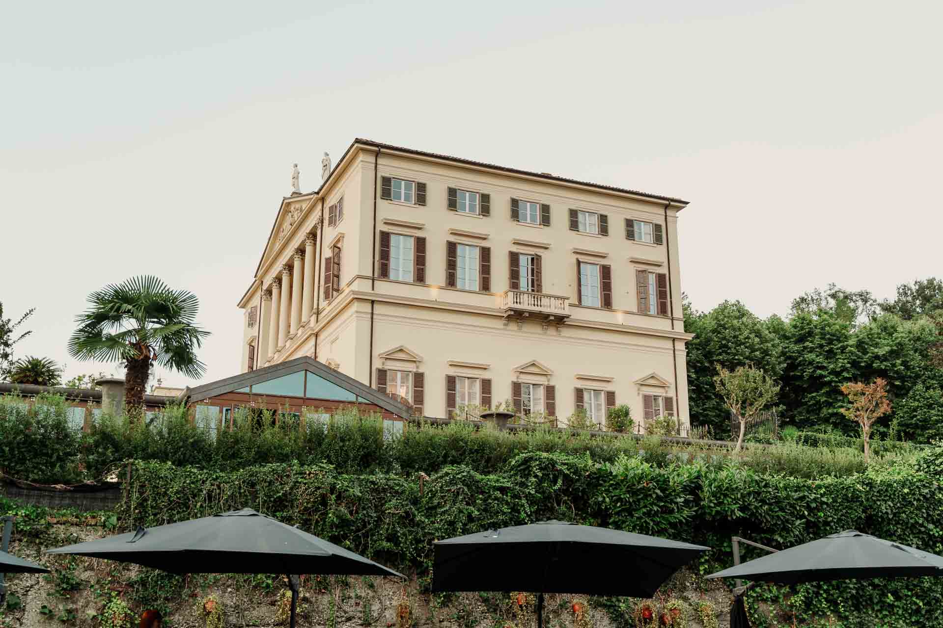 La villa vista dal giardino, con le palme e gli ombrelloni neri