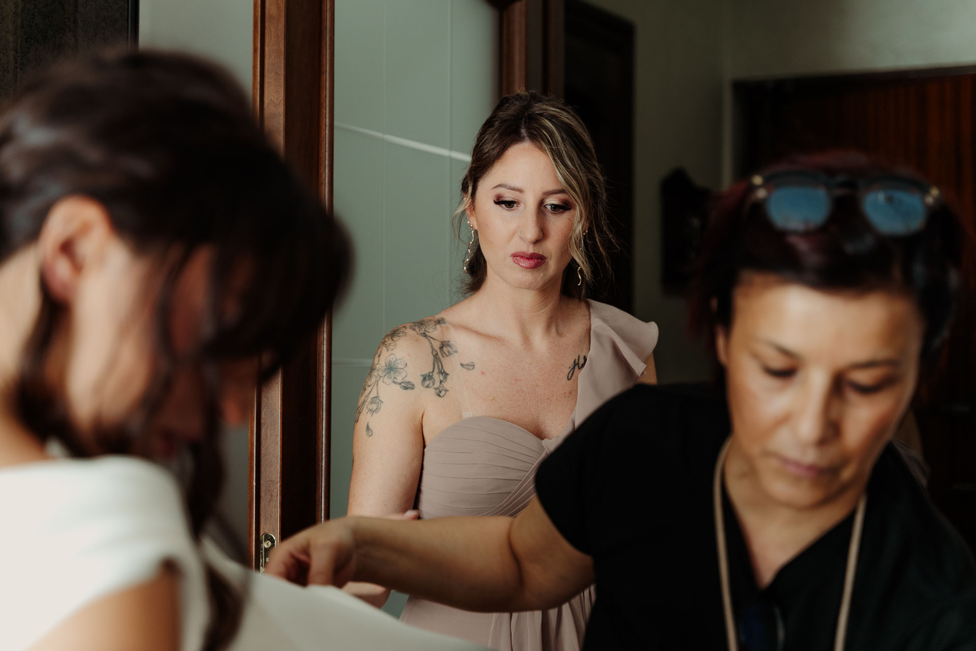 Le amiche e la truccatrice sistemano l'abito della sposa