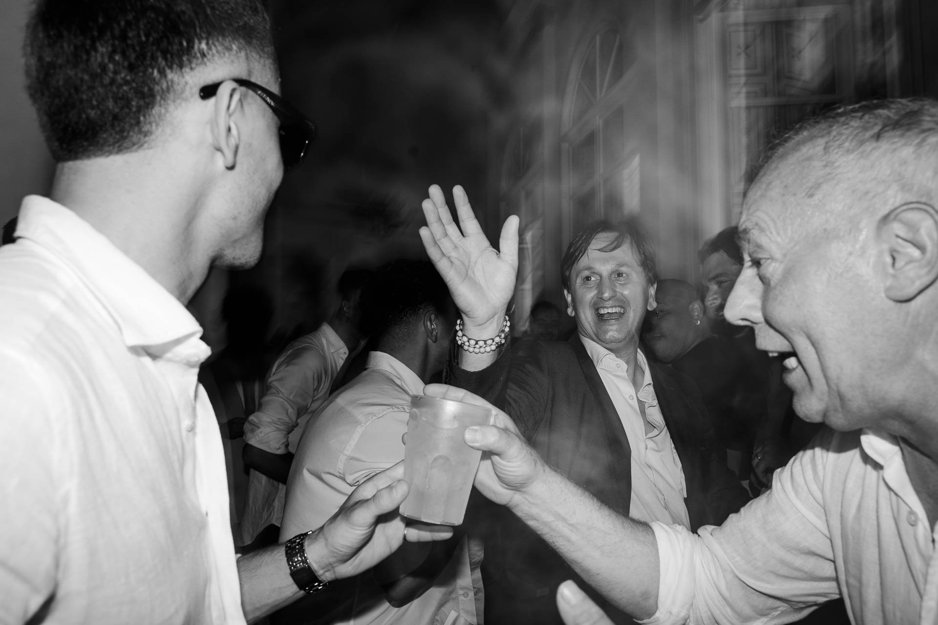 In bianco e nero, un amico brinda con un signore che ride, nel movimento della pista