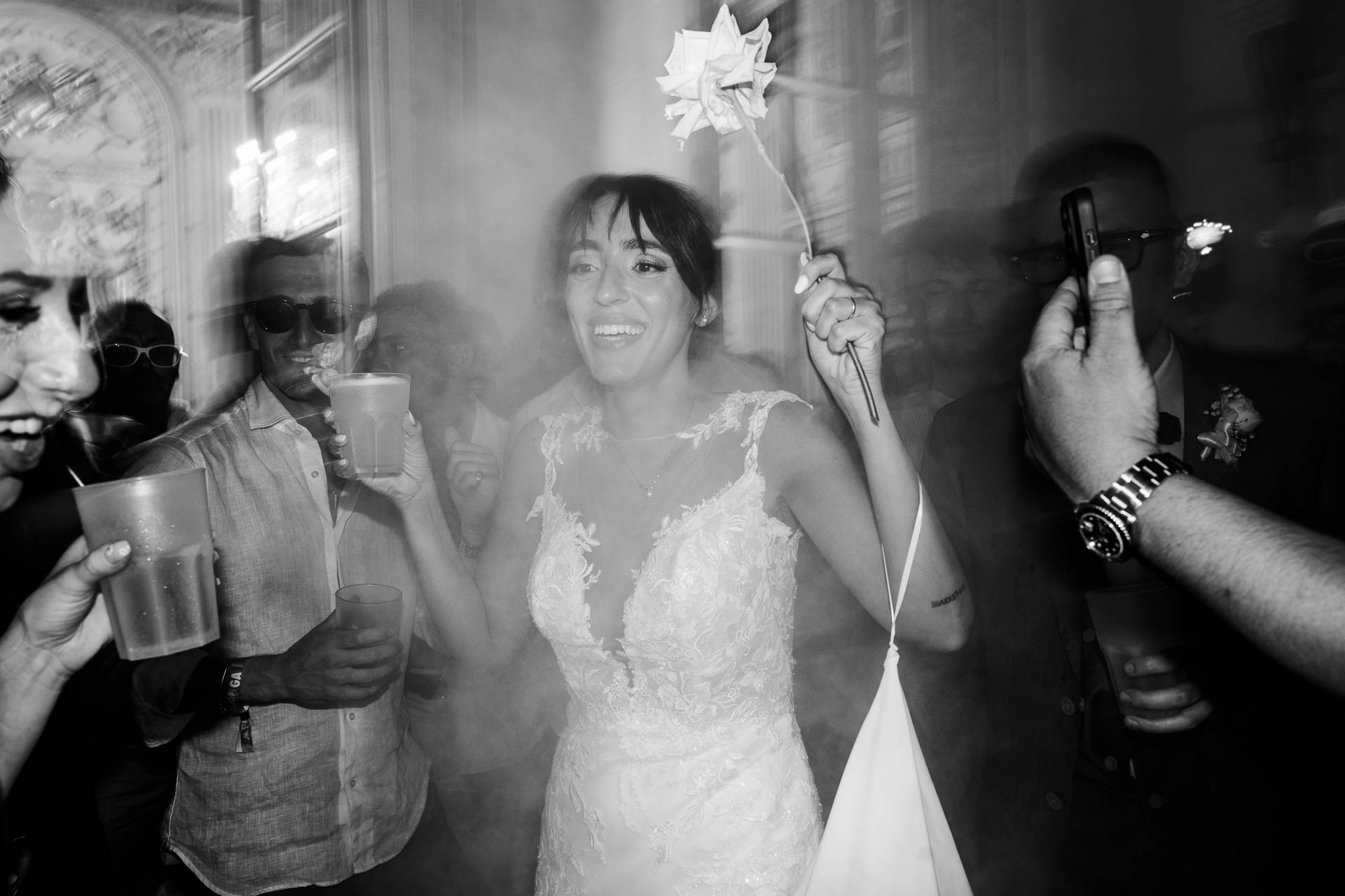 In bianco e nero, la sposa ride in mezzo alla pista con un girandolino in mano