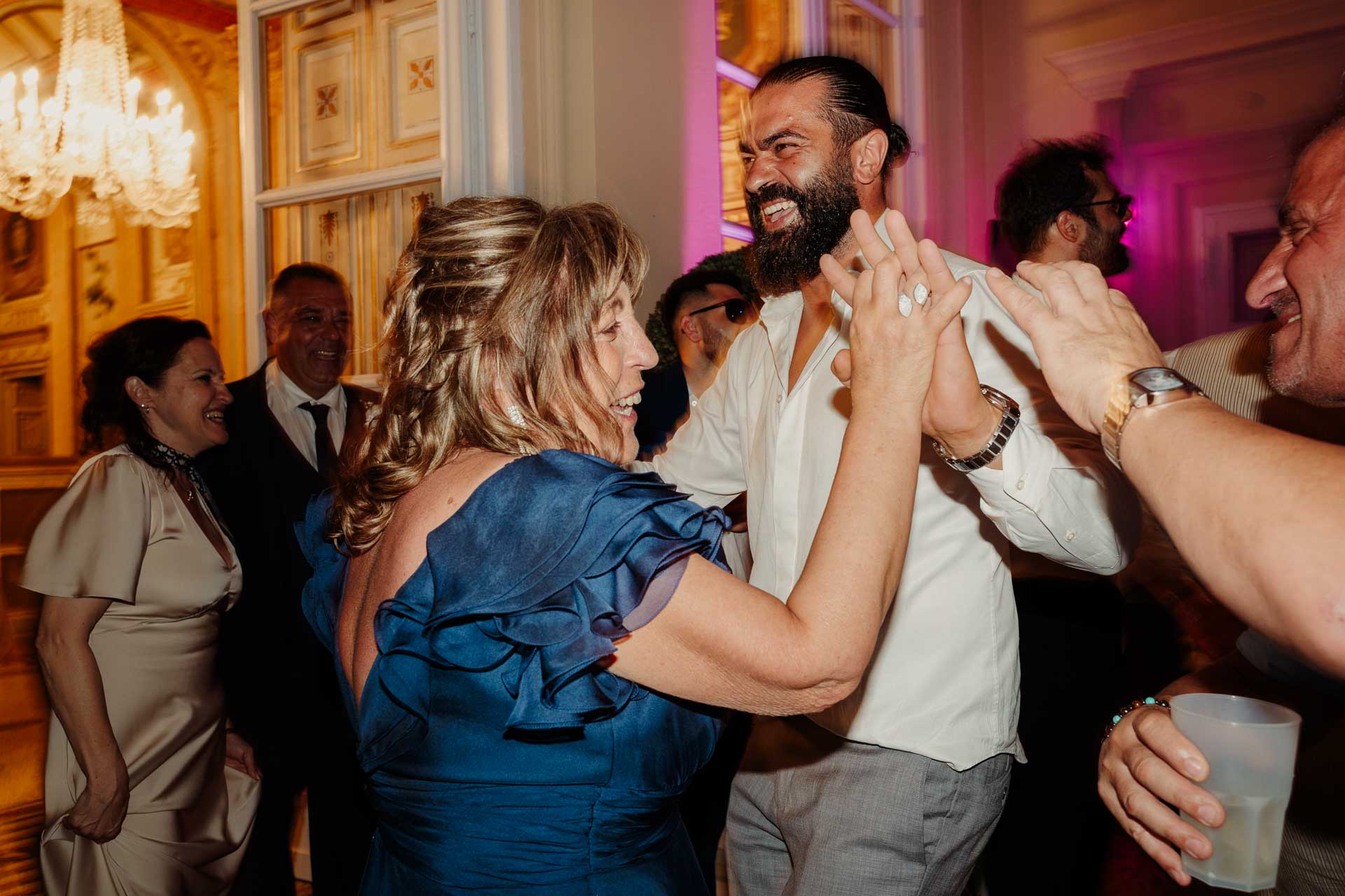 Una signora in abito blu e lo sposo ballano tenendosi per mano, tra gli invitati