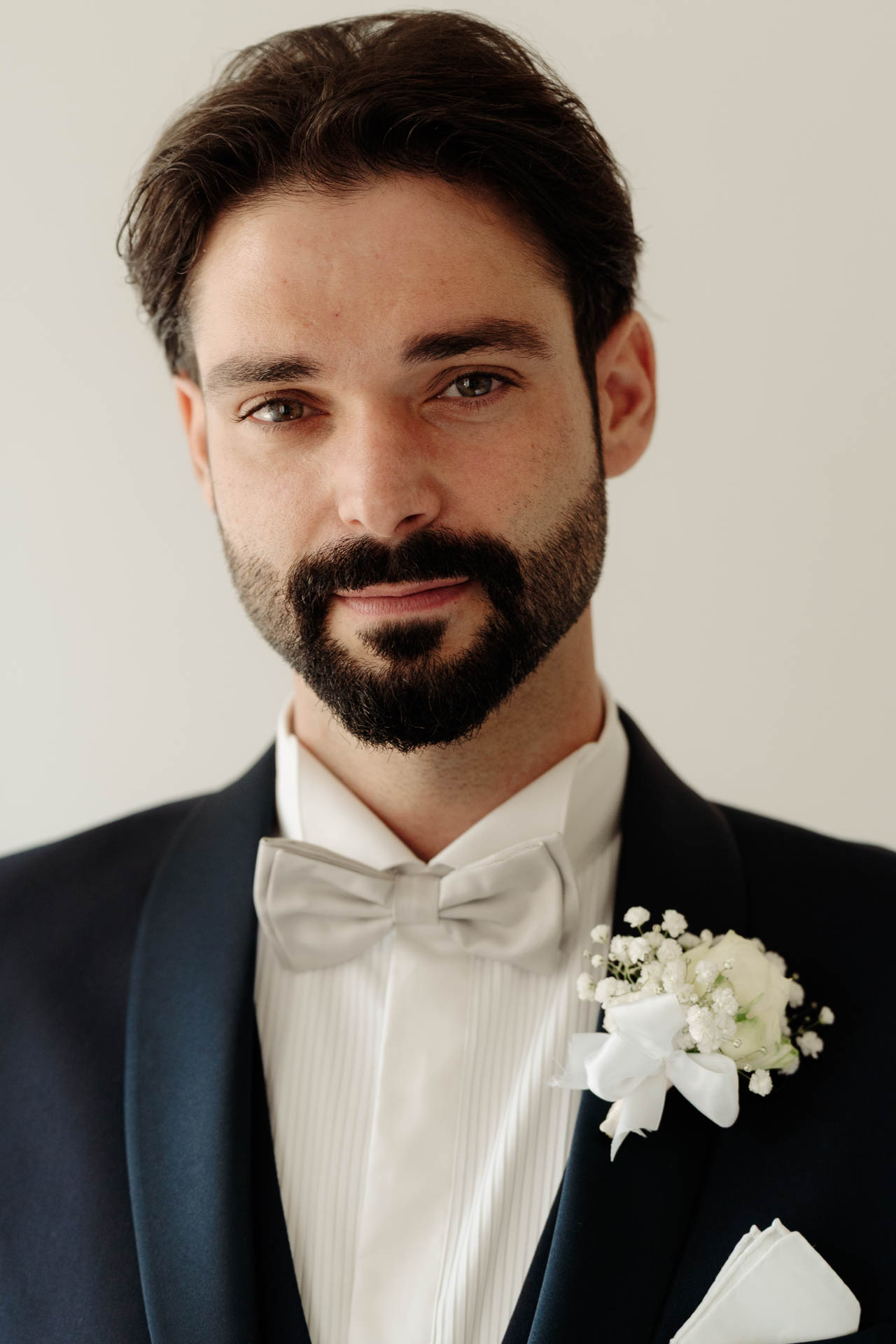 Ritratto dello sposo in smoking, con il papillon grigio e il fiore all'occhiello di gypsophila