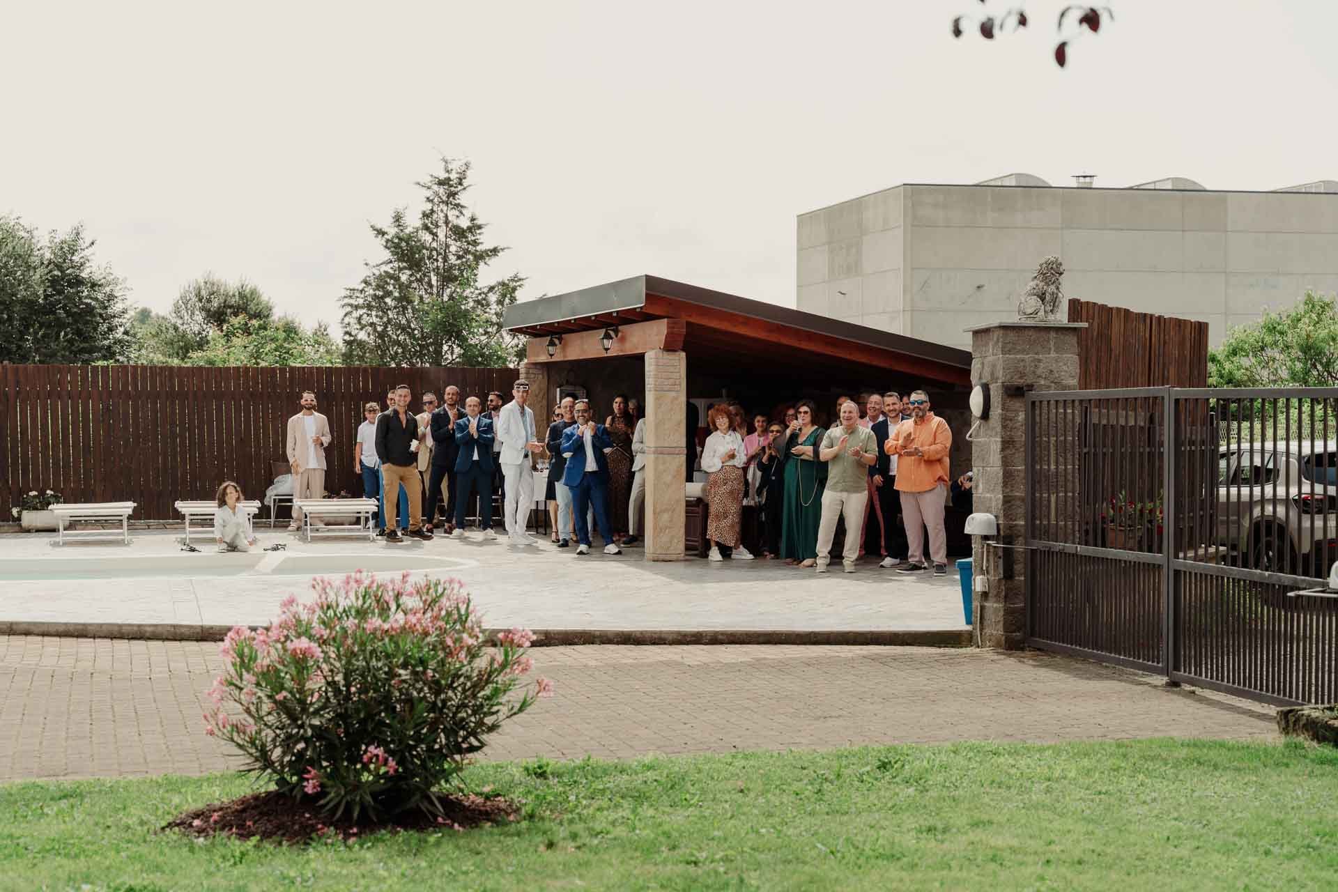 Gli invitati aspettano in fila sotto il portico del giardino, accanto alla piscina