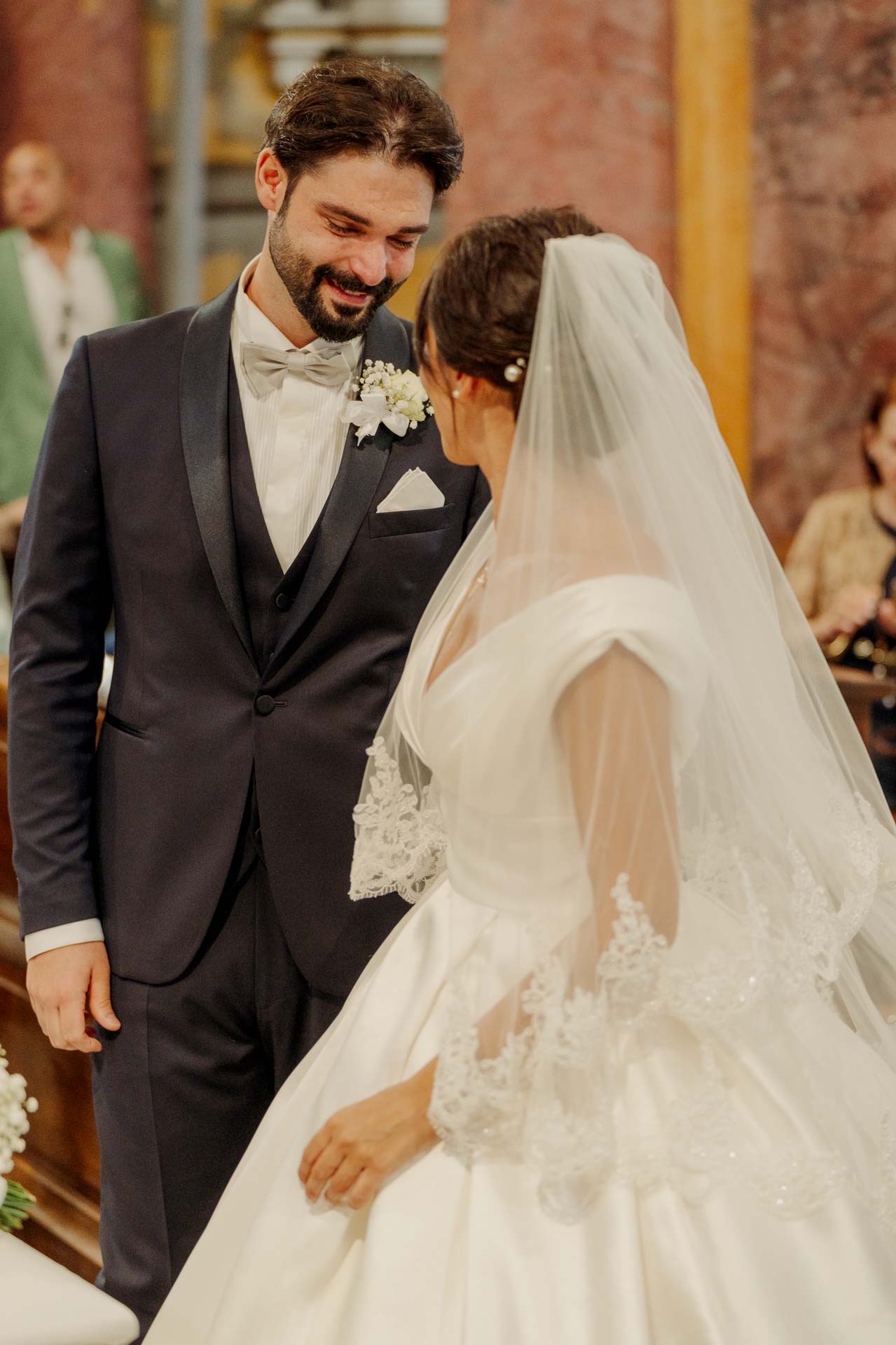 Lo sposo sorride alla sposa velata, davanti all'altare