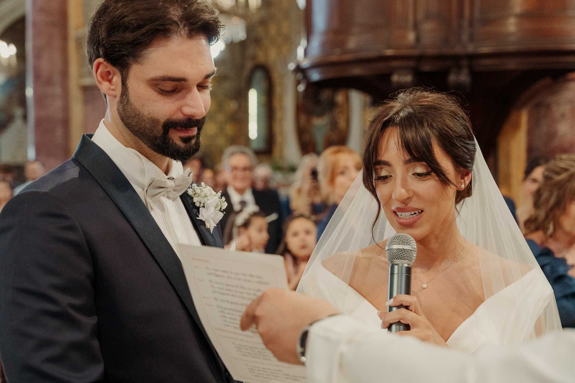 La sposa legge le promesse al microfono, accanto allo sposo