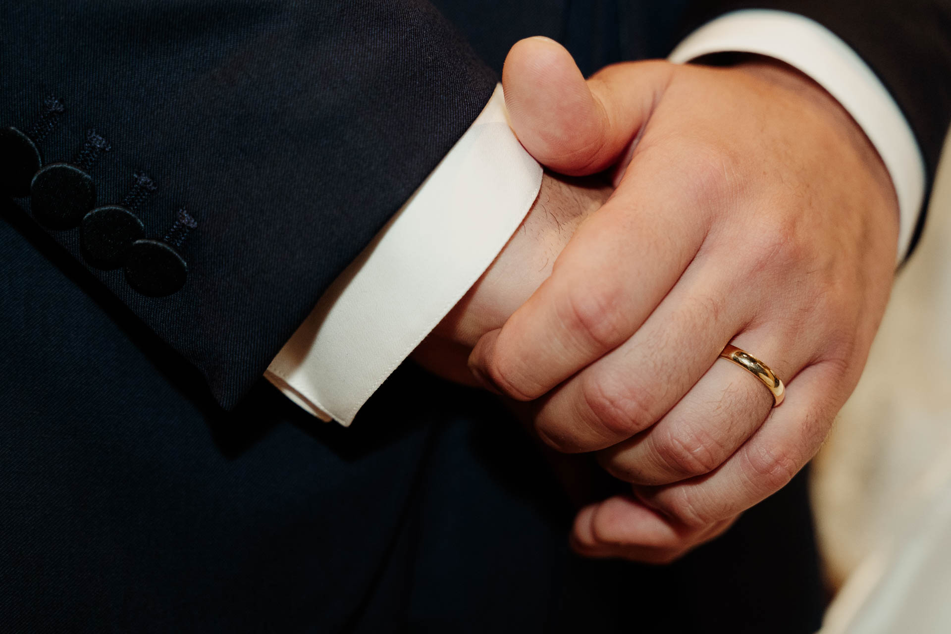 La mano dello sposo con la fede, sul polsino bianco della camicia