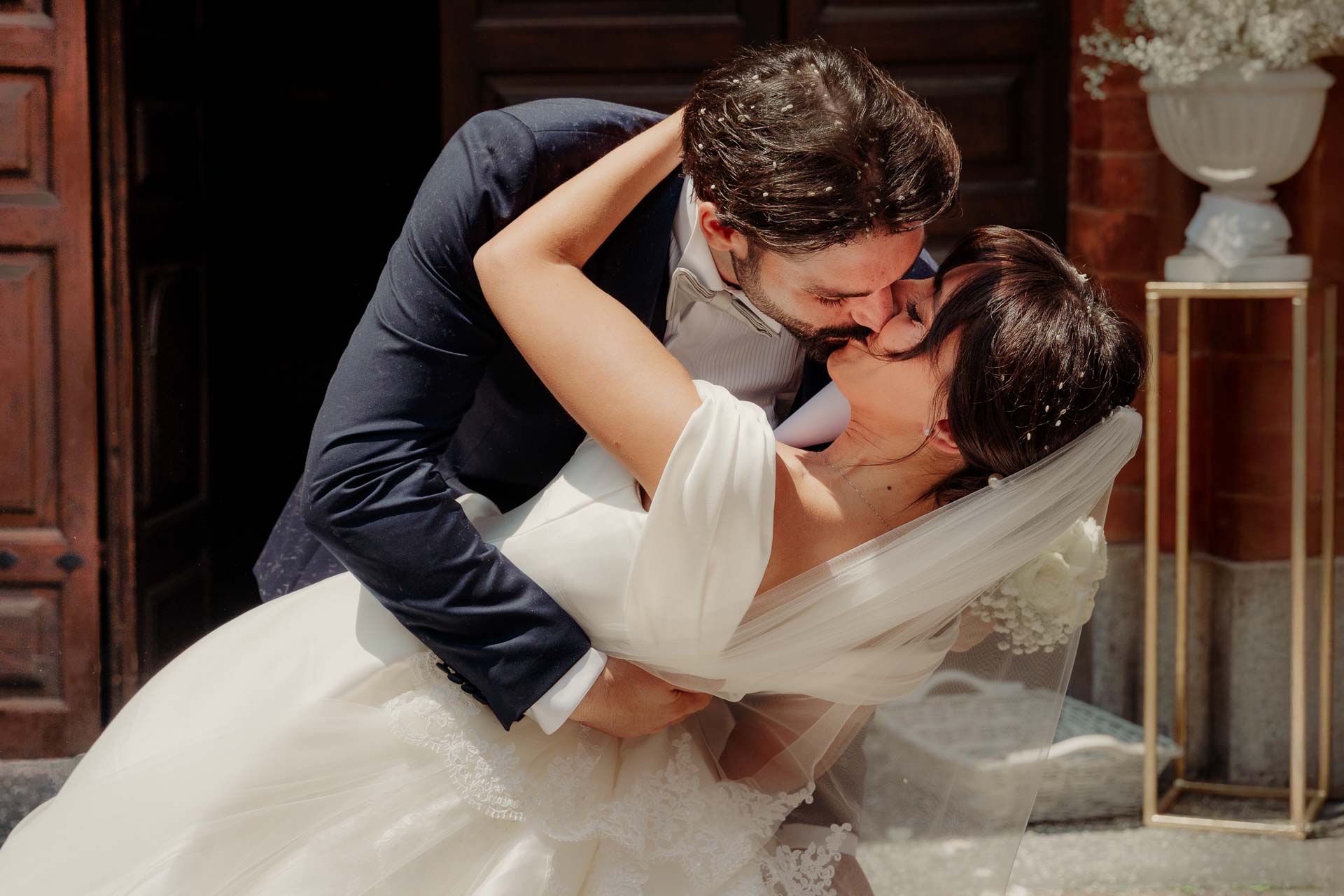 Lo sposo inclina la sposa in un bacio sul sagrato, davanti al portone