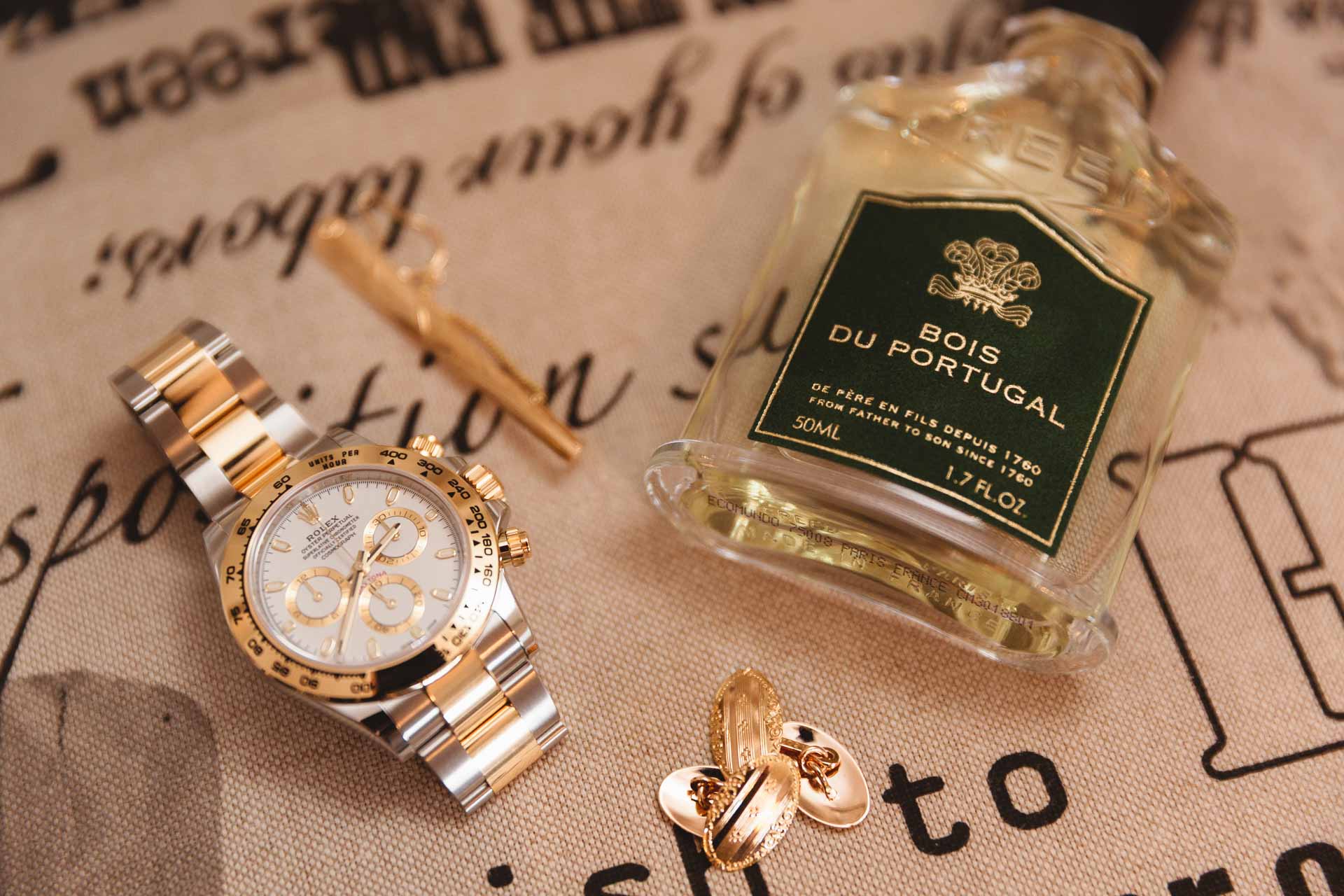 L'orologio, il profumo e i gemelli dello sposo su un tessuto stampato