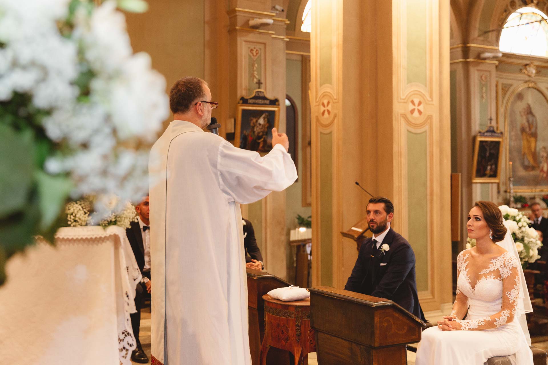 Il sacerdote durante la cerimonia, con gli sposi seduti all'altare