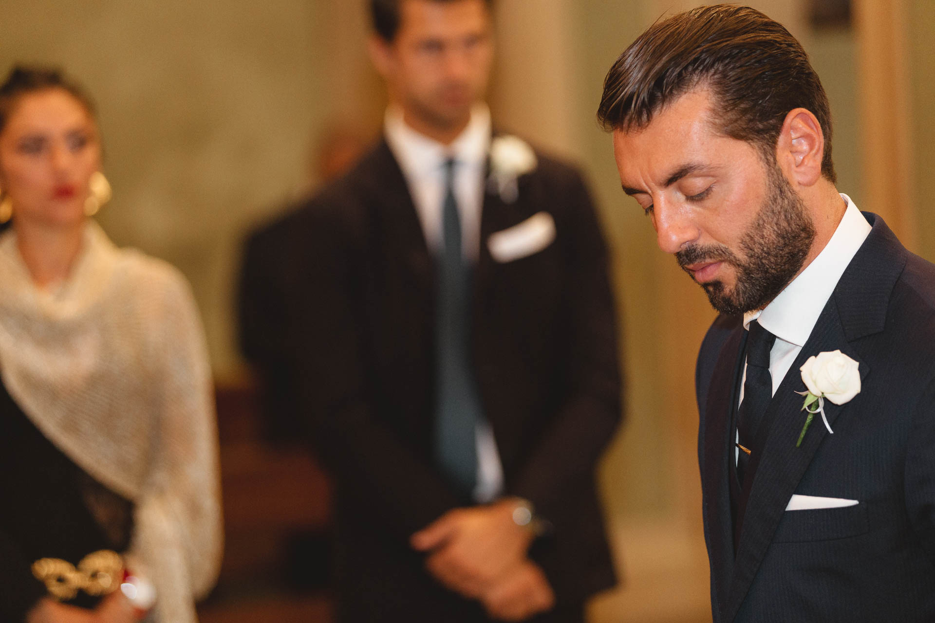 Lo sposo abbassa lo sguardo, con i testimoni dietro