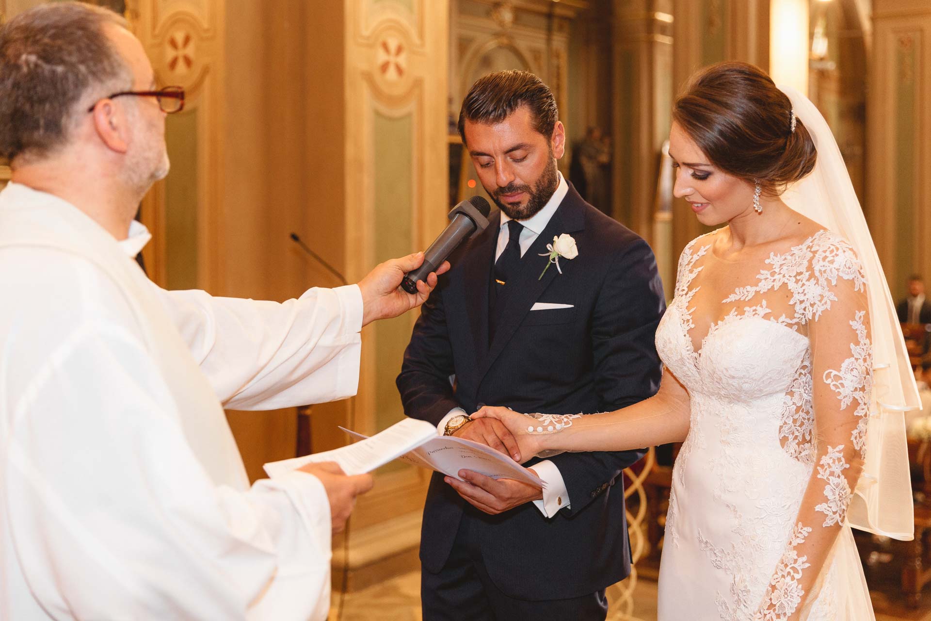 Lo sposo pronuncia le promesse, il sacerdote gli tiene il microfono