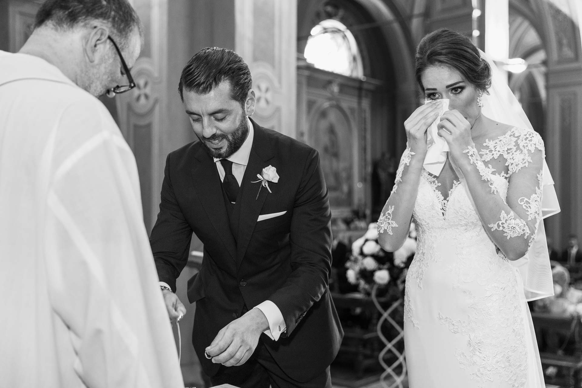 In bianco e nero, la sposa commossa si asciuga gli occhi e lo sposo sorride